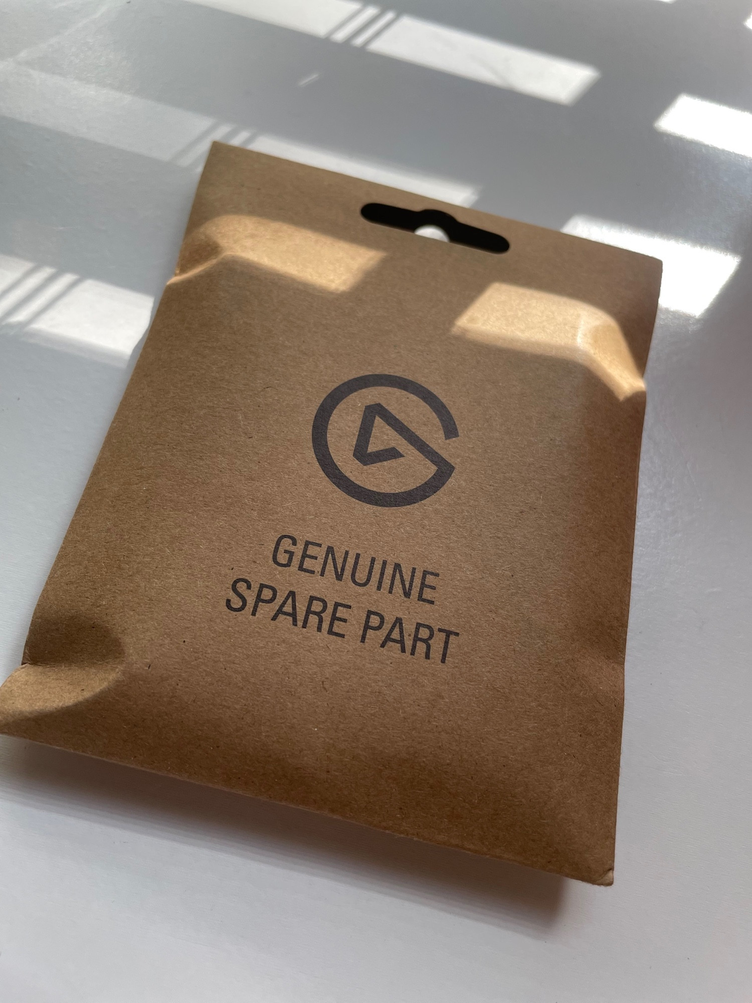 A brown little paper-like container that has the Elgato emblem and says, “Genuine Spare Part.”