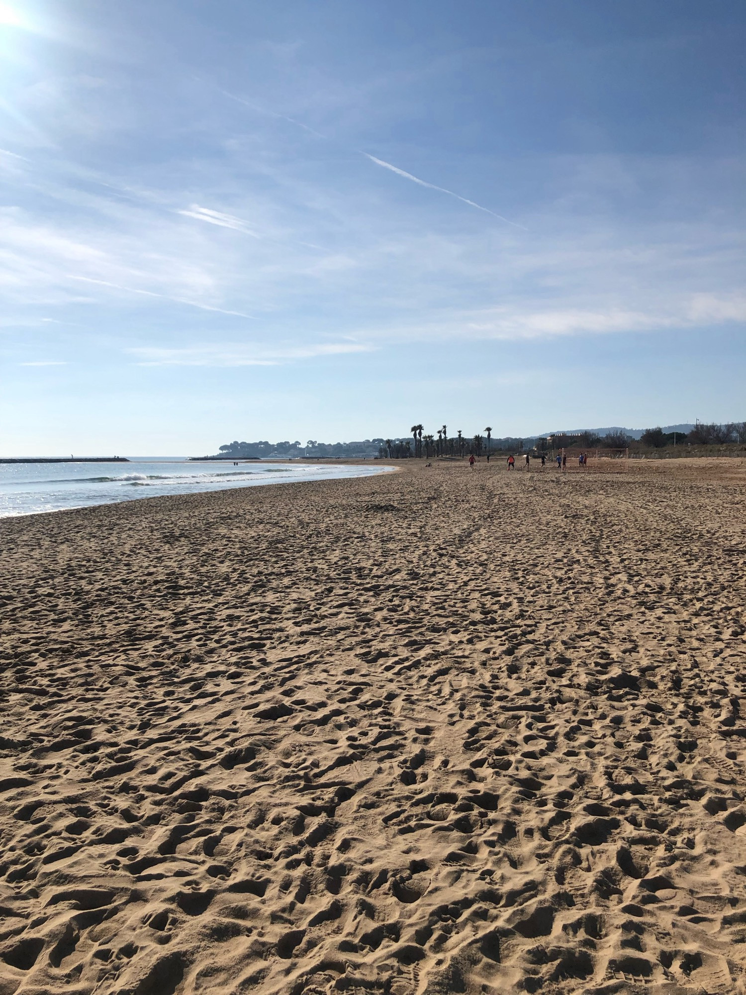 Une plage de sable sans personne , à gauche la mer qui scintille. Le ciel bleu clai avec quelques nuages. Saint Aygulf, avril2024