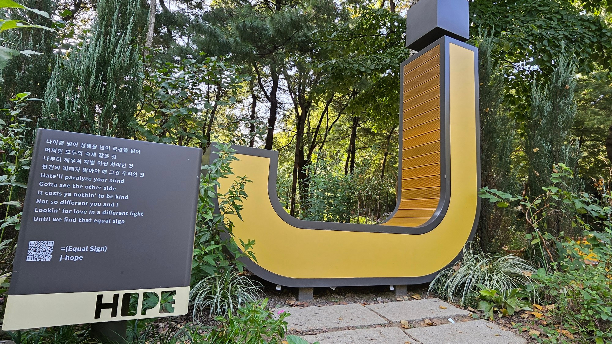 J-Hope (from the group BTS) bench, which is a yellow J, in Seoul Forest along with lyrics from his song 'Equal Sign' 