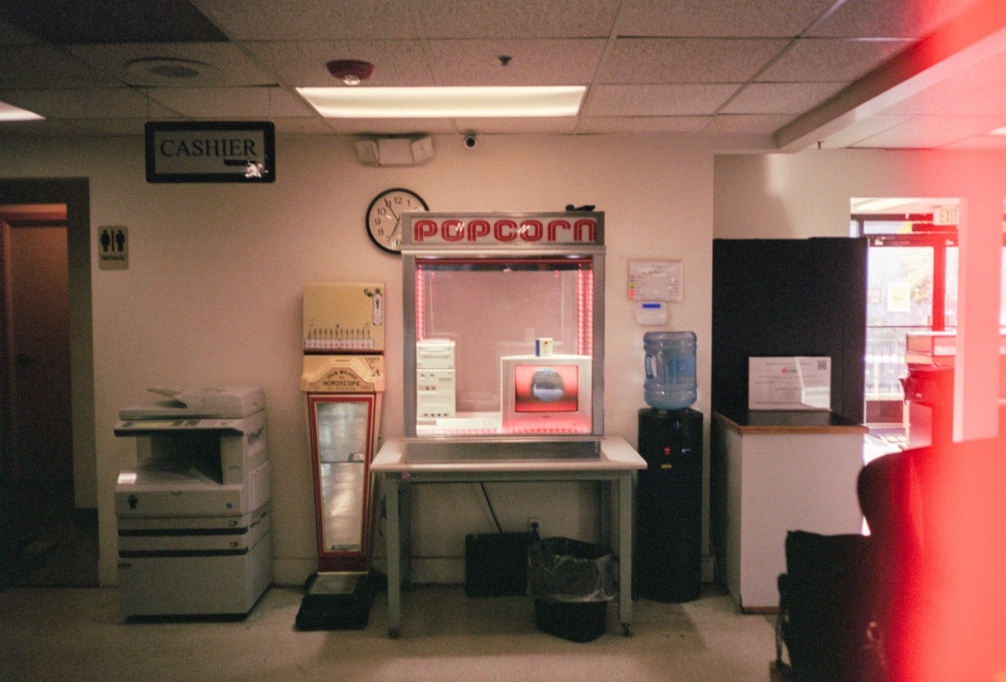 A photo centering the popcorn machine containing a Sega Dreamcast development kit inside of REPC next to a copier and a water cooler.