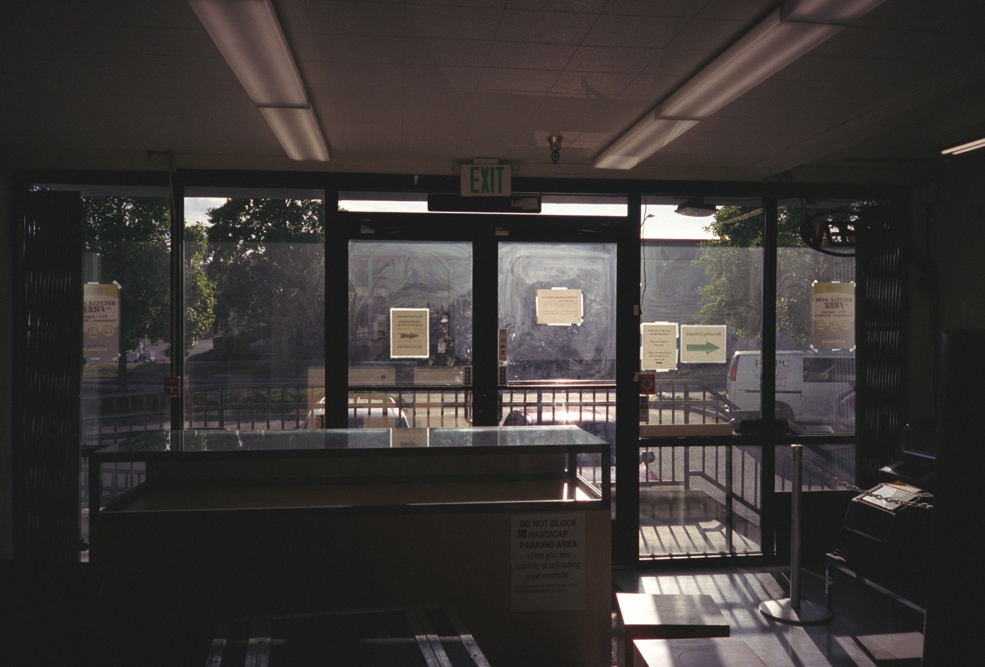 A photo taken from inside REPC Tukwila's front doors, looking outside. The windows are a bit smudged, but some of the outside is visible. It's dark inside and the sun is at a low angle coming in.