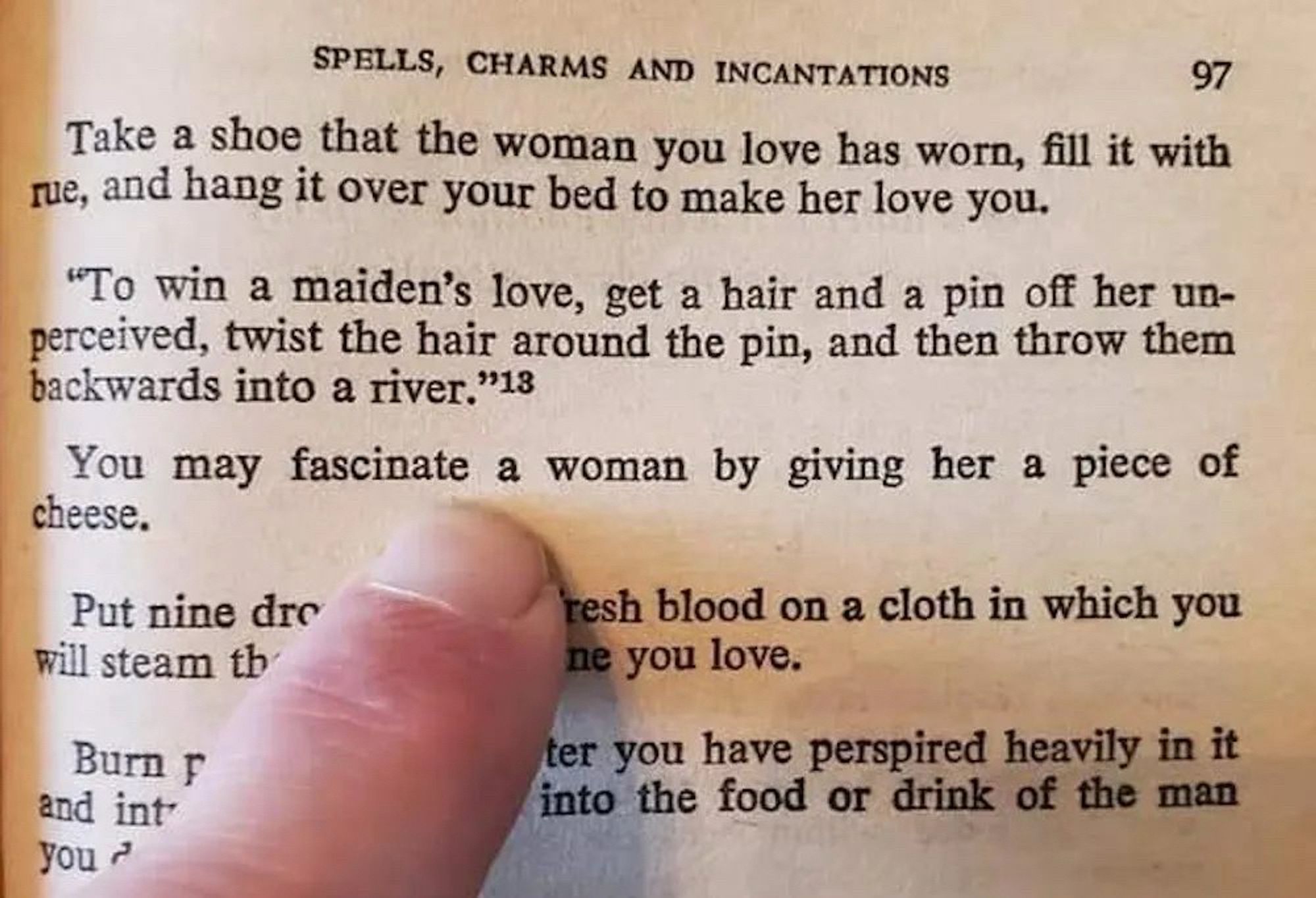 A book of spells, charms and incantations turned to the section that is for wooing a lady. Someone’s finger is pointing at one that says: You may fascinate a woman by giving her a piece of cheese.