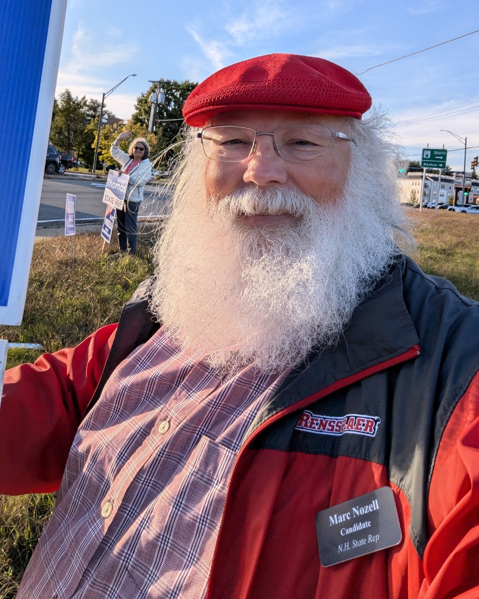 Marc Nozell and Wendy Thomas (background) holding signs for our campaigns + Harris/Walz