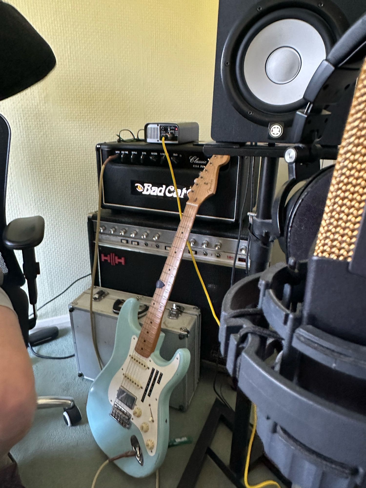 A Fender Stratocaster guitar resting on an old 1970s amplifier with a microphone just in shot.