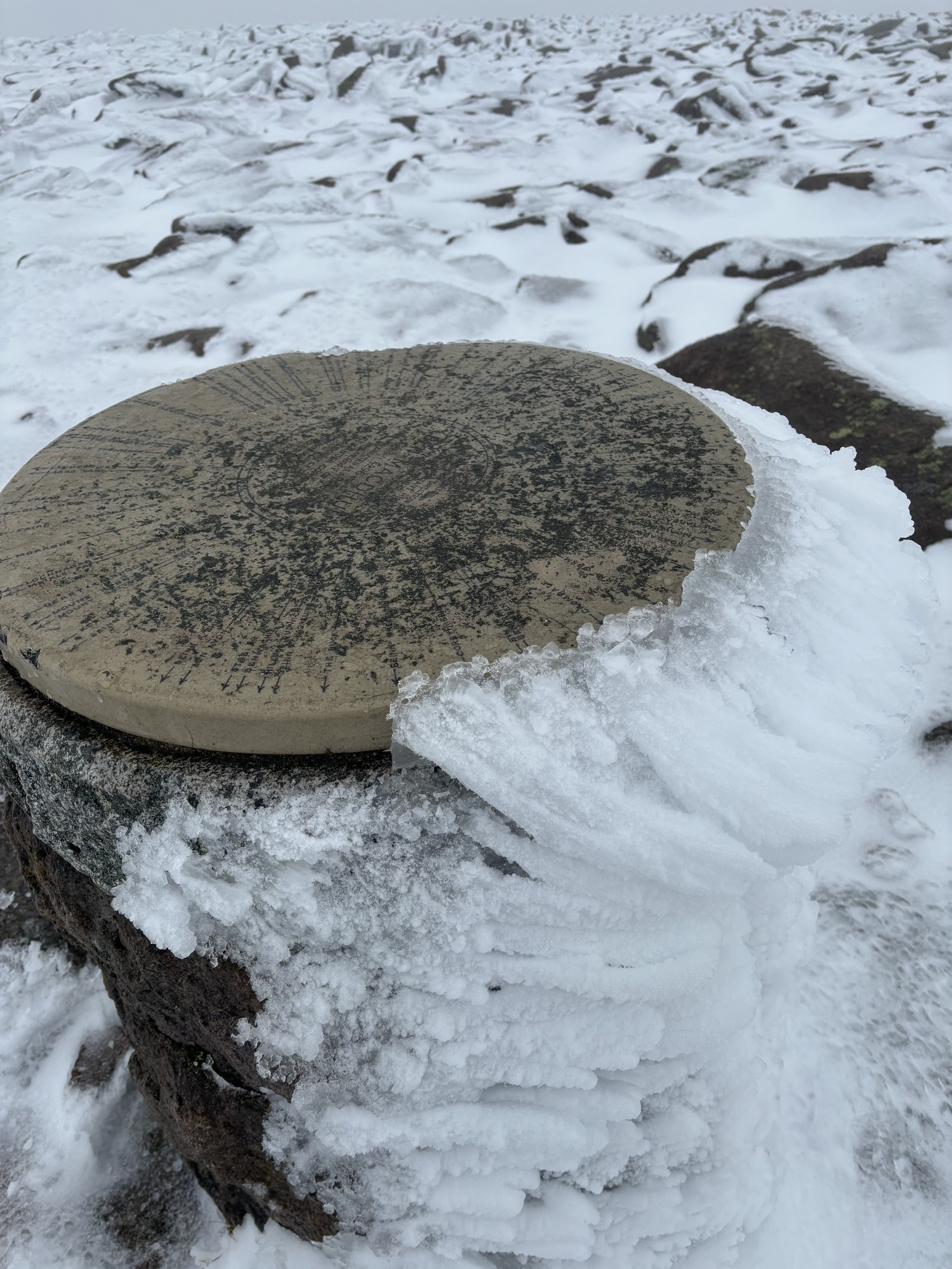 The summit indicator on Ben Macdui. Ice is covering one side of the plinth. 