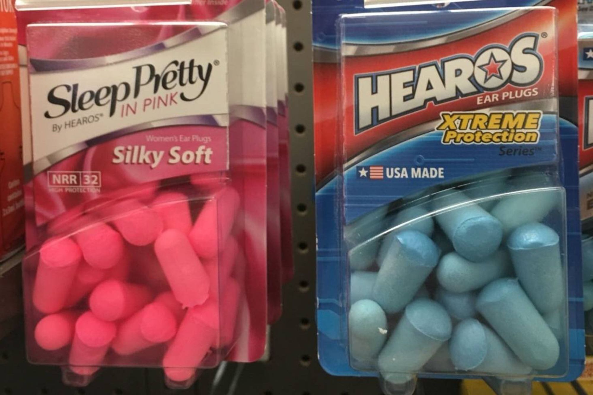 Photo of a store shelf with two sets of earplugs marketed to women and men respectively - “Sleep Pretty” which are in pink, and “Hearos XTREME Protection” which are in blue