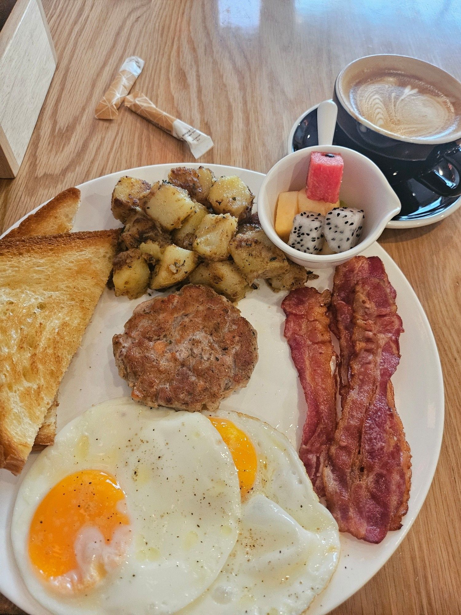 "Egg breakfast", with sausage patty, eggs how I like, fried bread, fried potato, bacon, and some fruit chunks that I don't know what to do with (fortunately, they're in a side dish)