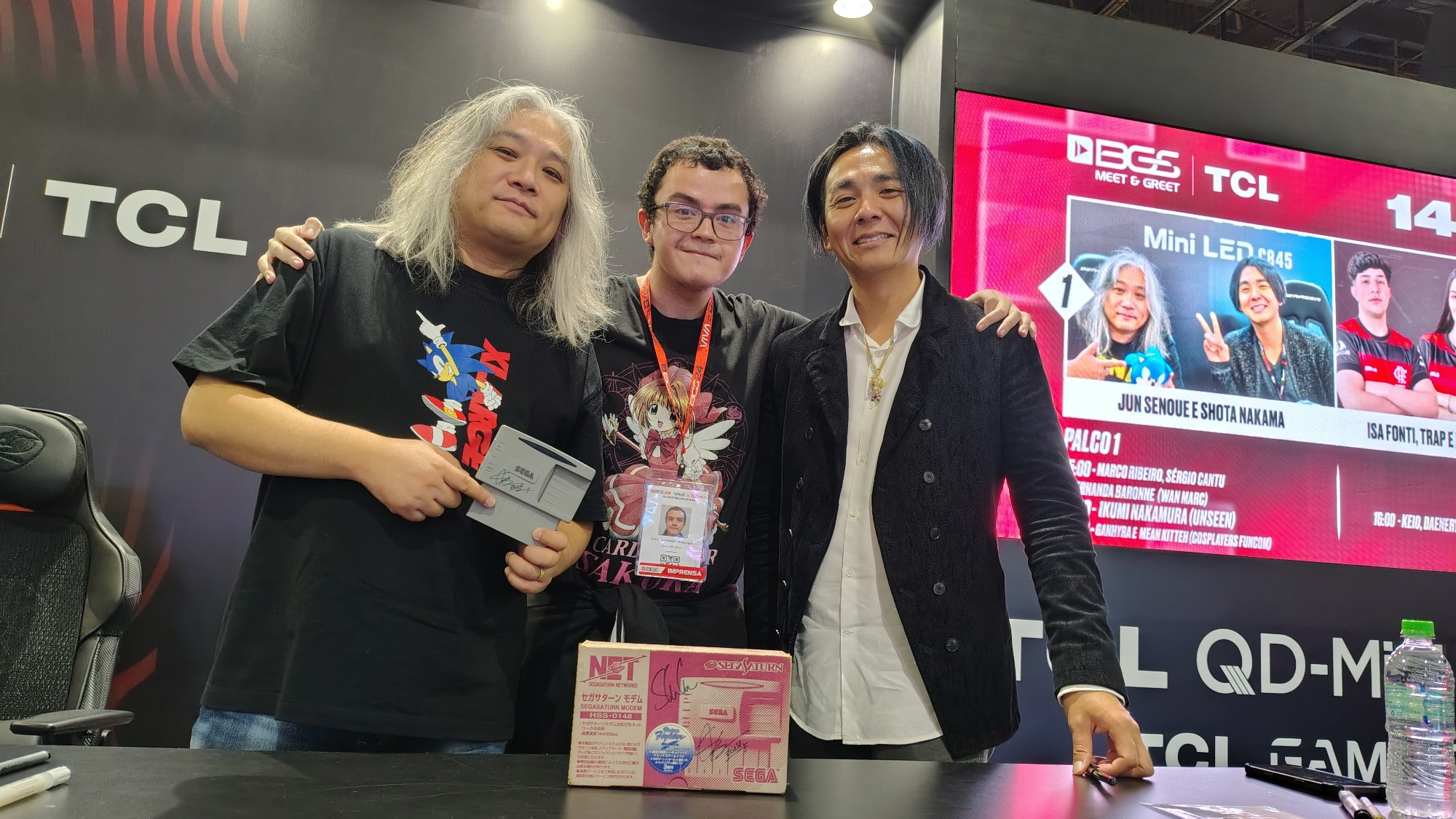 Jun Senoue segurando o modem XBAND de Sega Saturn, eu (Yuri Suetsugu) no meio, e Shota Nakama com a caixa no Modem na mesa