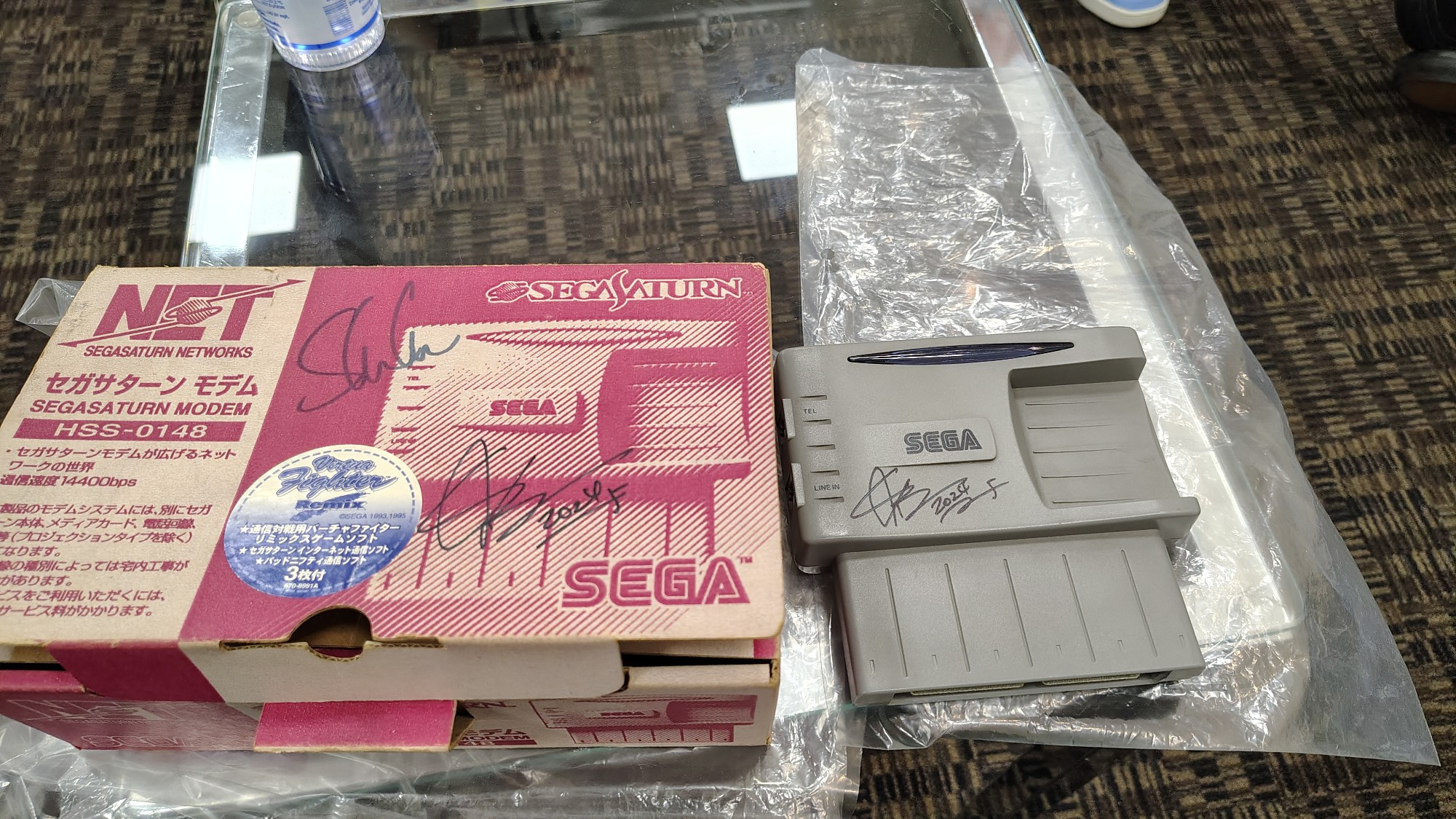 Caixa e Modem Japonês do XBAND pra Sega Saturn autografados por Jun Senoue e Shota Nakama