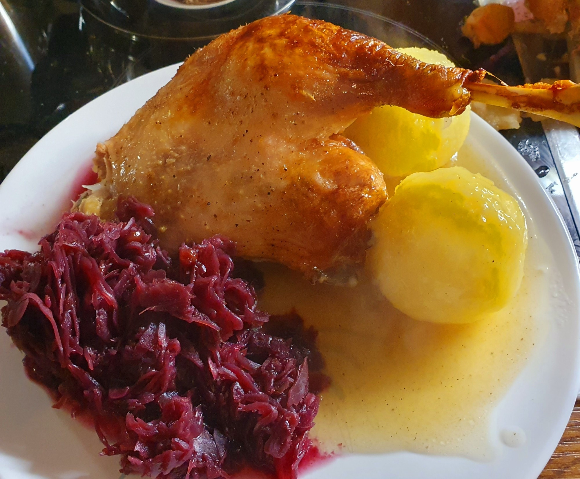 Ein Teller mit einem Viertel einer Weihnachtsgans, Knödeln, Blaukraut und Sauce.