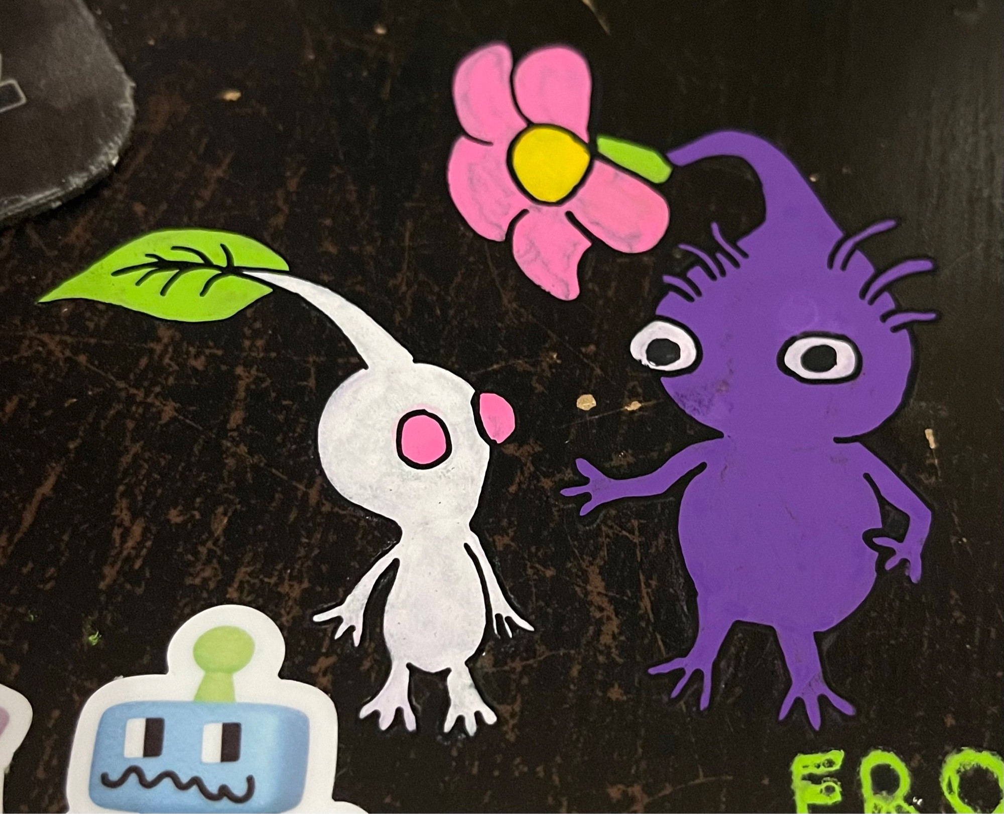 doodles of a White and Purple Pikmin, done in Posca pens on a black desk