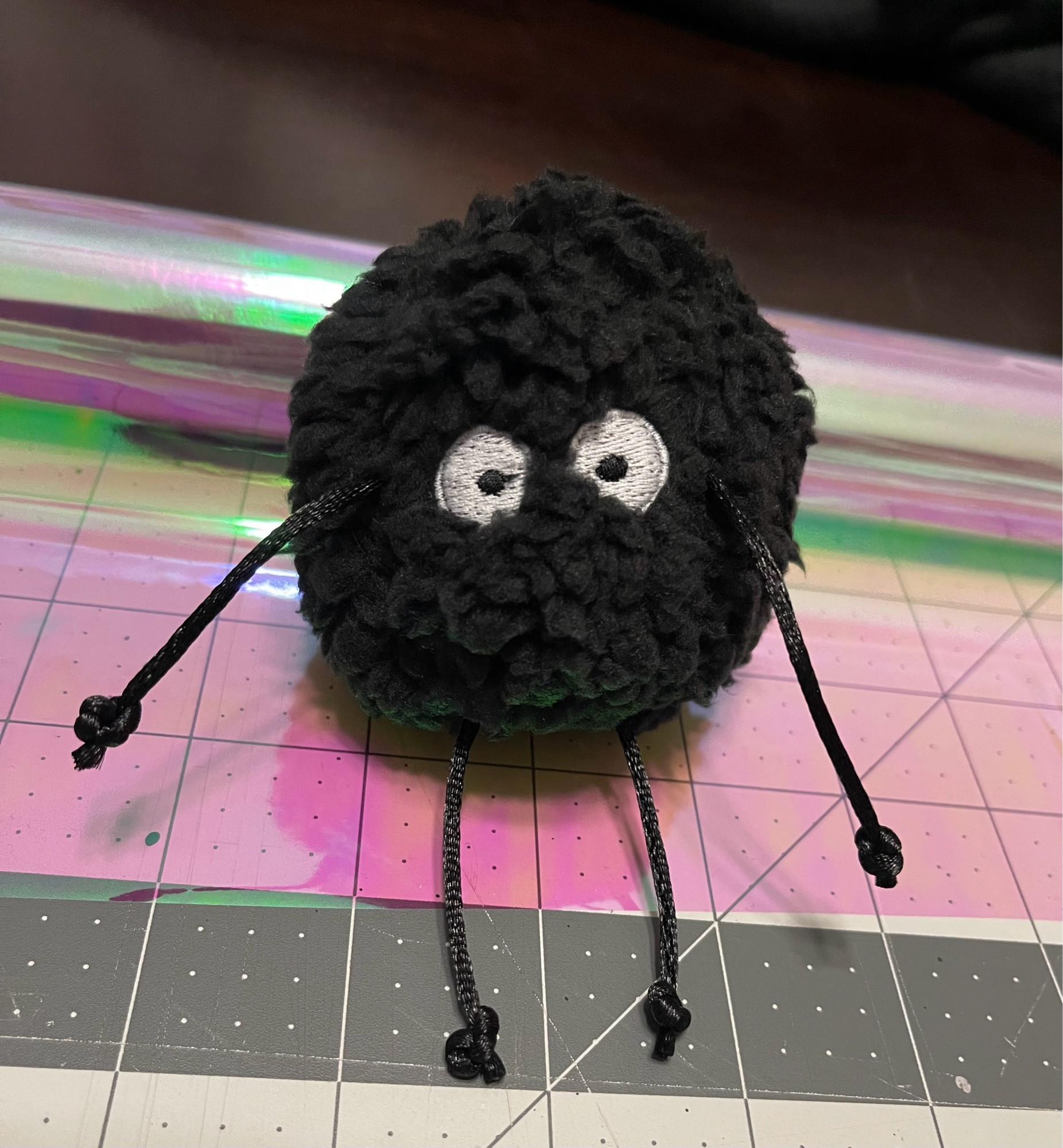 handmade plush of a Soot Sprite from the Ghibli films, made with a fuzzy sherpa fabric, embroidered eyes, and dangly string limbs