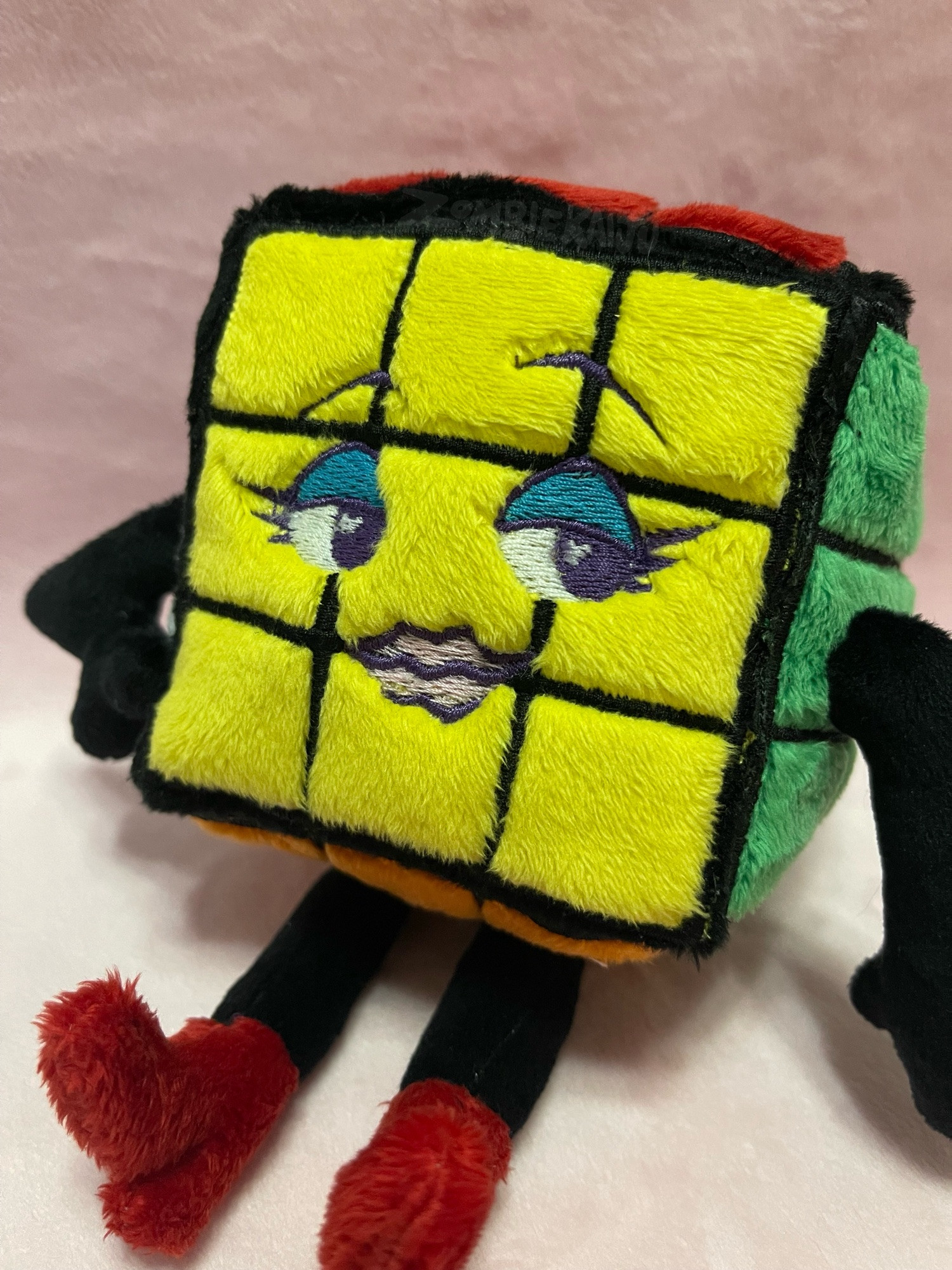 a handmade plush of a rubiks cube with arms and legs (and red boots) with a sexy face embroidered on the front