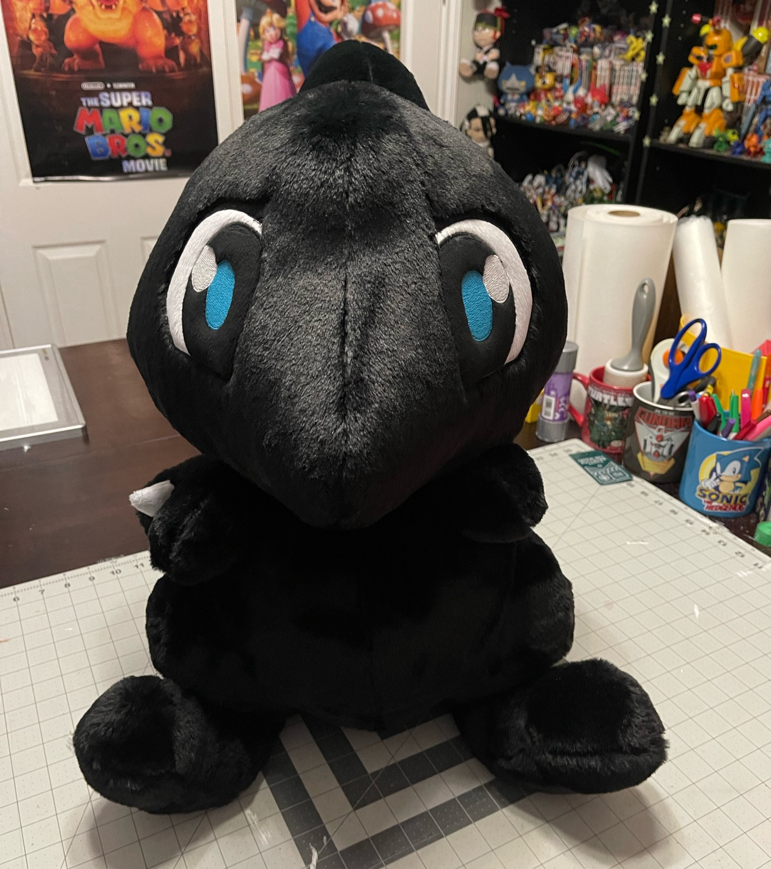 Very big (about 24” tall) handmade plush of a Shadow Shoyru from Neopets, which is a black cartoon dragon with blue eyes and little wings, made with a very fluffy fabric.  Plush is facing directly forward