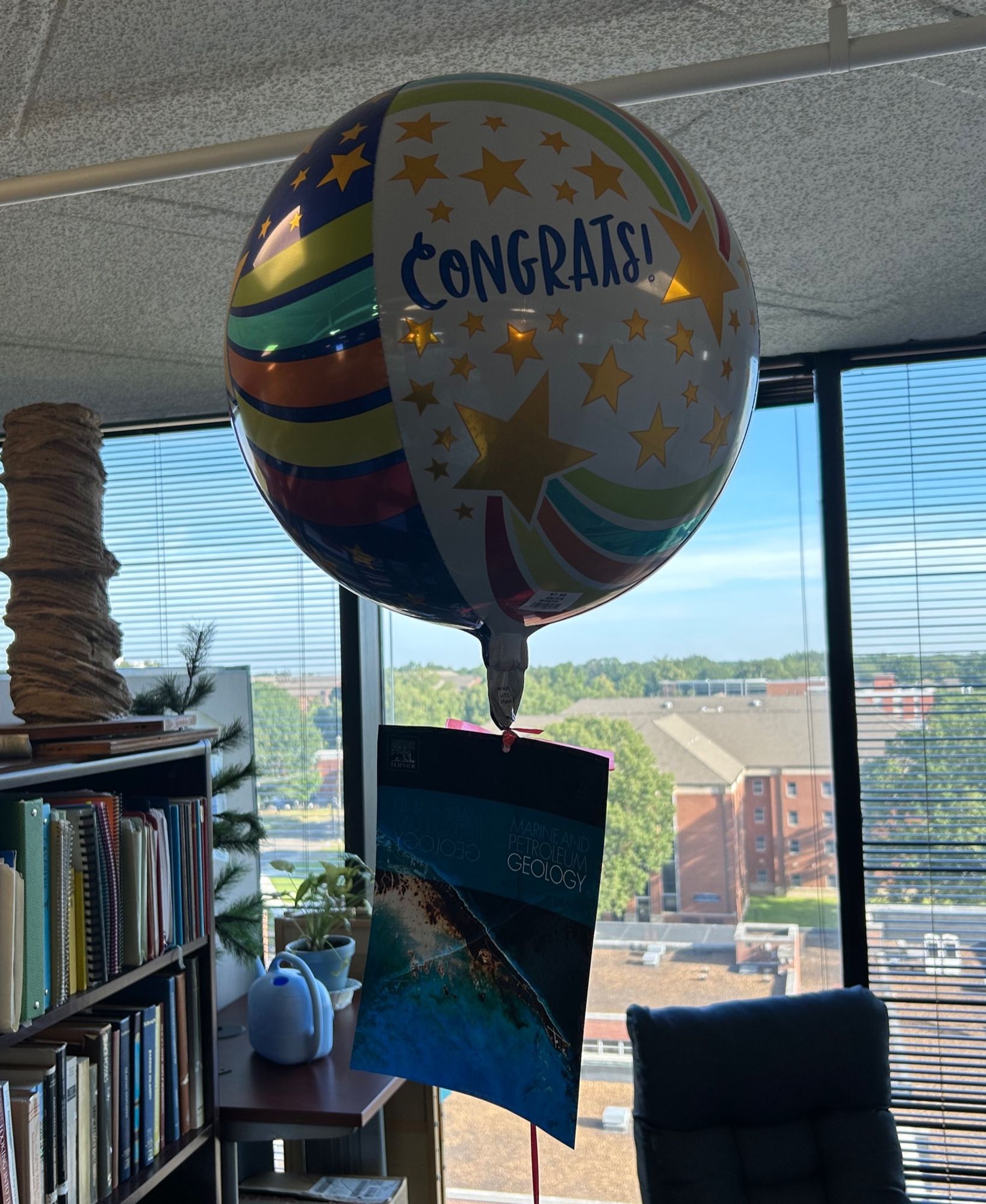 Balloon that says CONGRATS with an academic journal title page hanging on the string.