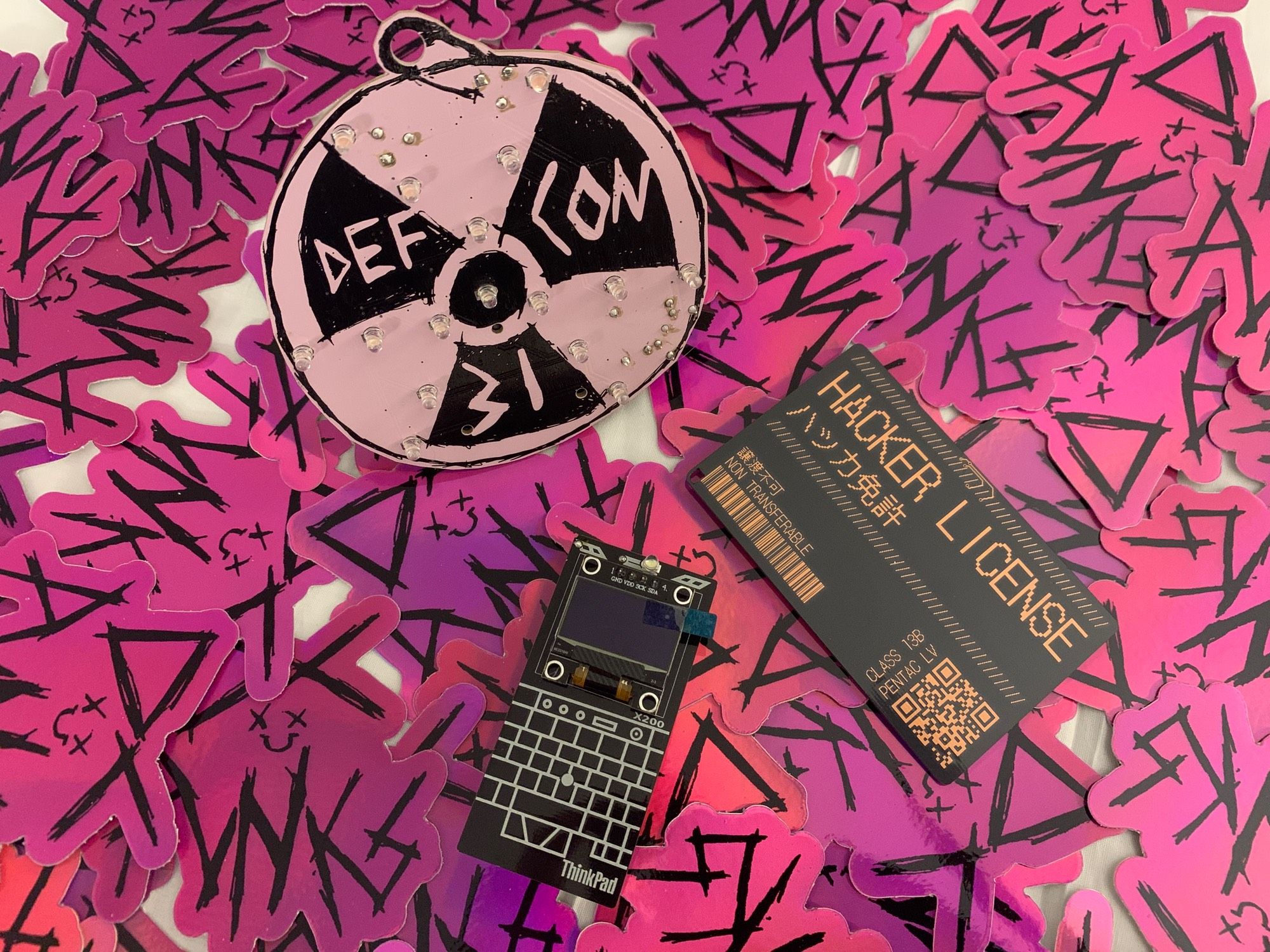 Colorful PCB badges that light up when turned on in front of a background of shiny magenta DCPunks stickers 