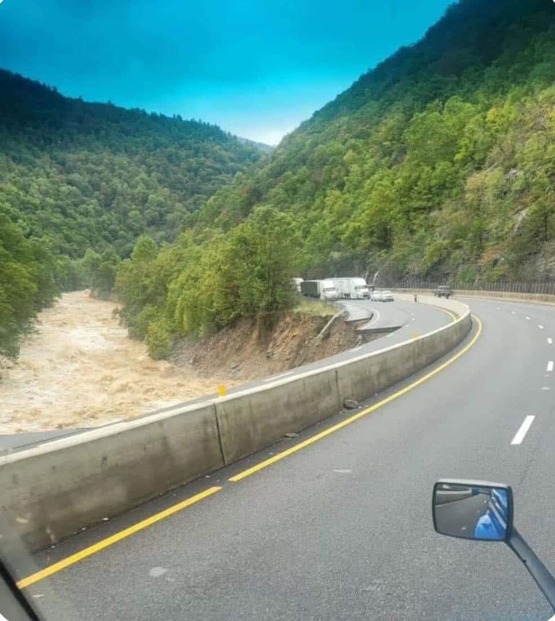 Photo of I-40 near Harewood Cty, showing that a stretch of I-40E has been washed away. In the distance are several lorries and other traffic, which have been stalled by the washout.