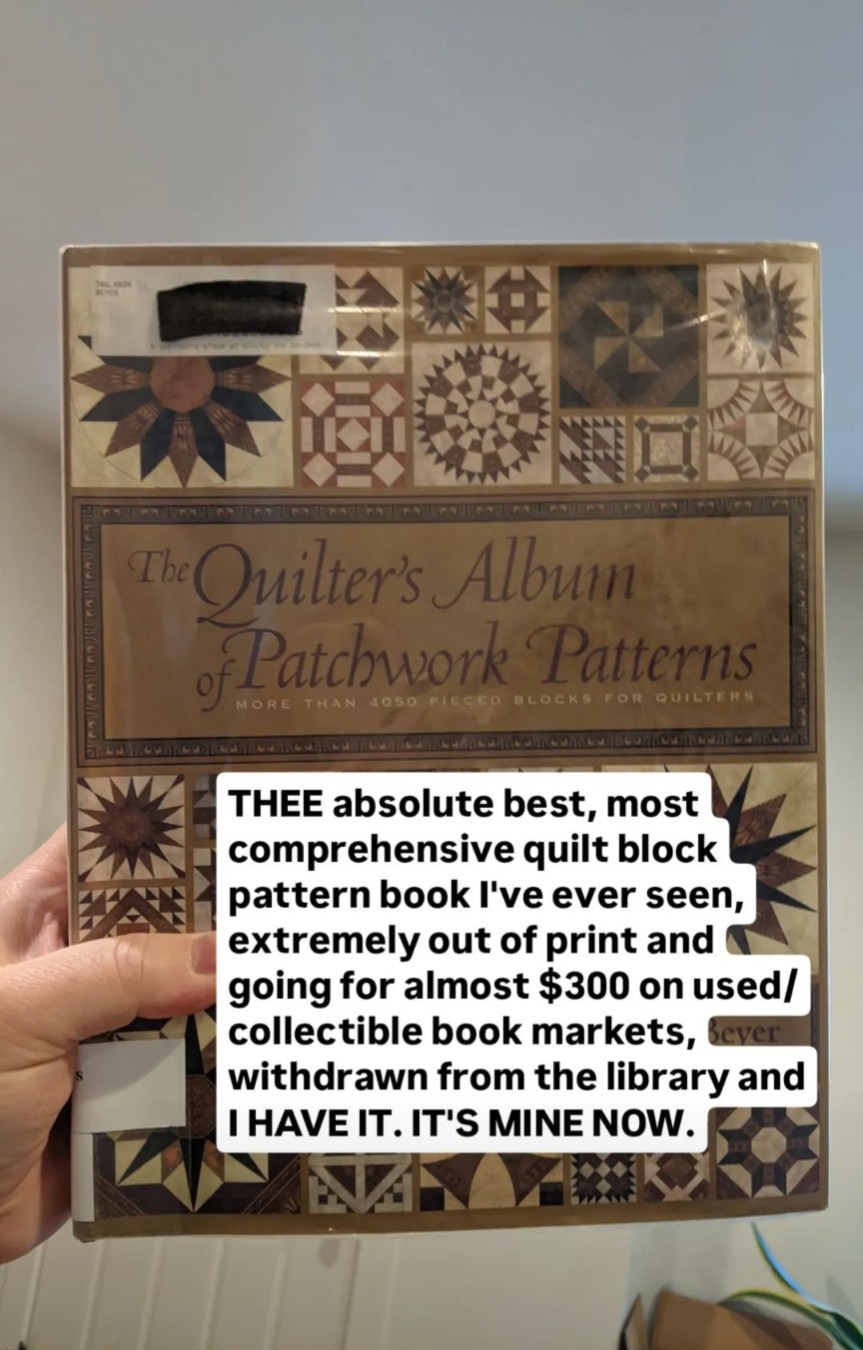 Hand holding copy of "The Quilter's Album of Patchwork Patterns" by Jinny Beyer. Superimposed text on image reads "THEE absolute best, most comprehensive quilt block pattern book I've ever seen, extremely out of print and going for almost $300 on used/collectible book markets, withdrawn from the library and I HAVE IT. IT'S MINE NOW."