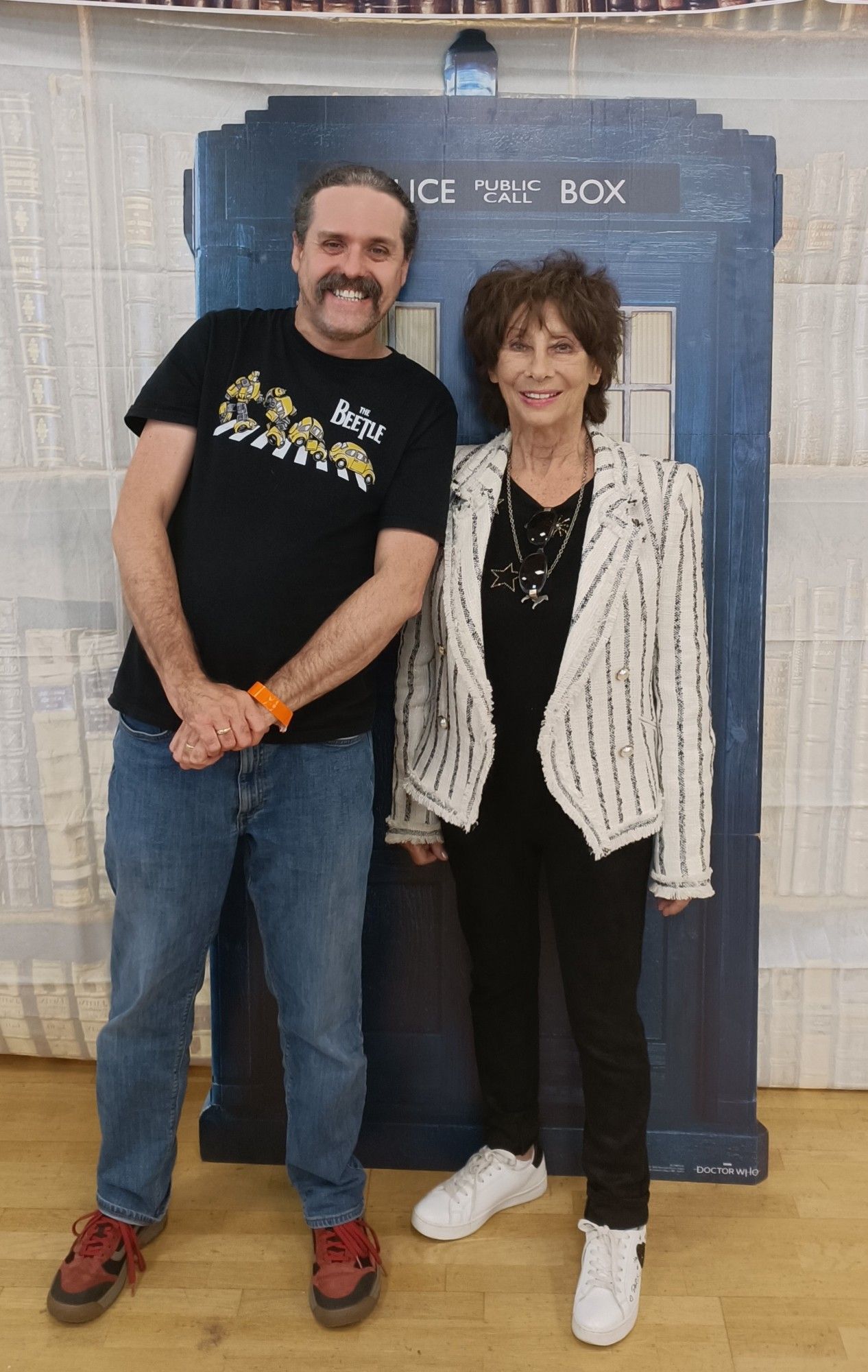 A mustachioed twit, grinning, in front of The Tardis, alongside The Doctor's granddaughter.