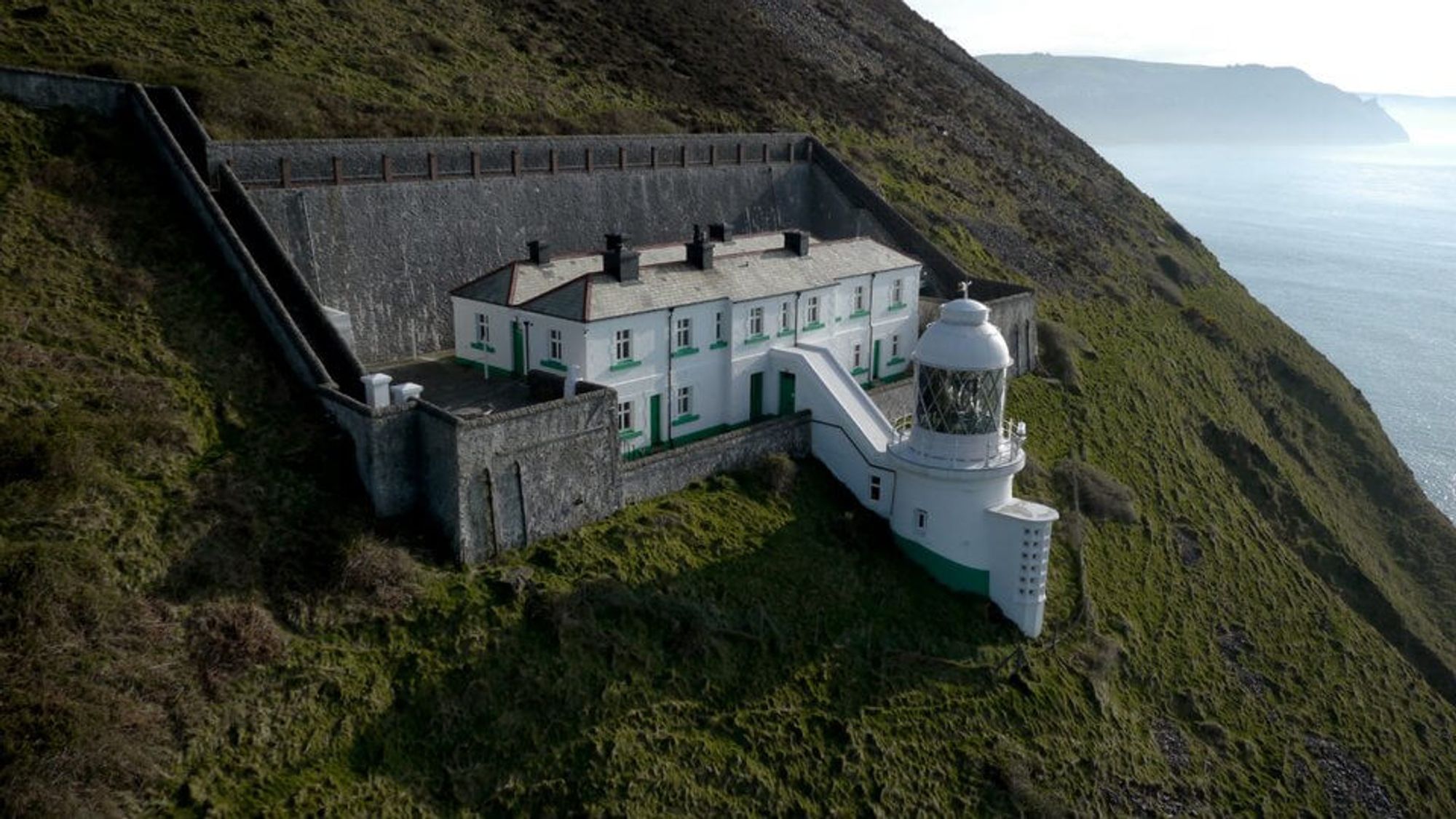 Lighthouse on the edge of a cliff facing the sea