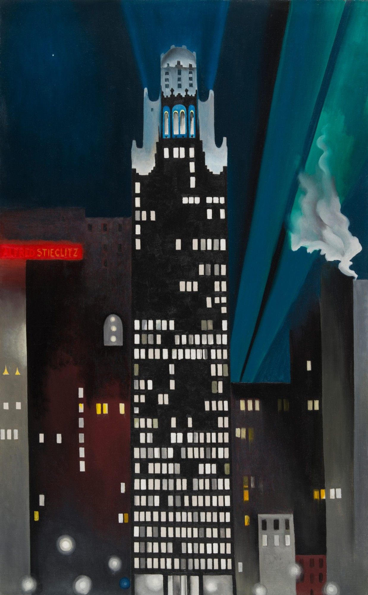 Radiator Building—Night, New York, 1927. A skyscraper at night, black with many illuminated windows, with distinctive bright, curved decorative elements at its top. The sky is broken up by searchlights and smoke. We also see what looks like a neon-red sign that says Alfred Stieglitz.