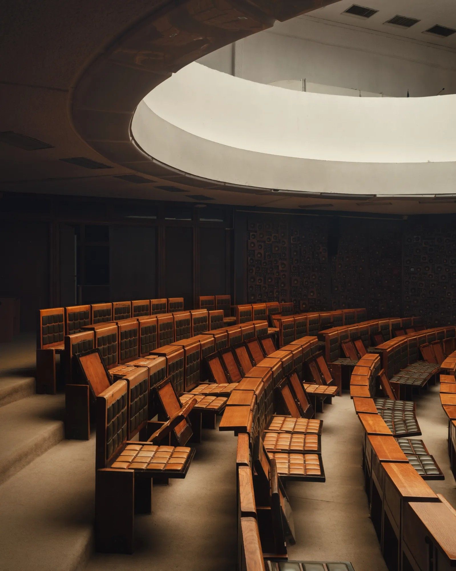 Interior of main auditorium, showing rows of theater-style pull-down seats with matching grids of squares on seats and backrests. Photo by Oskar Proctor.