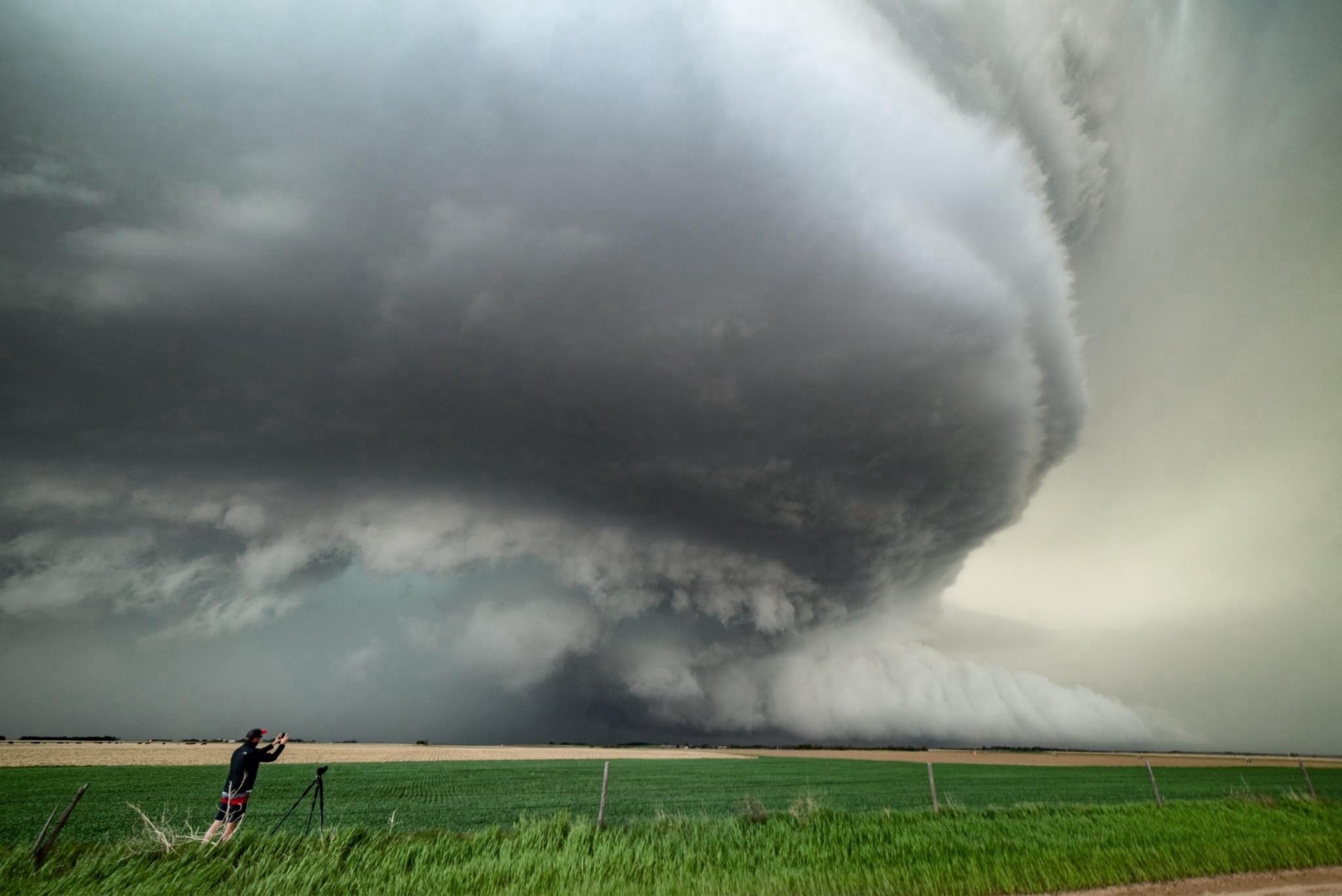 A man photographs a massive supercell looming in the distance.