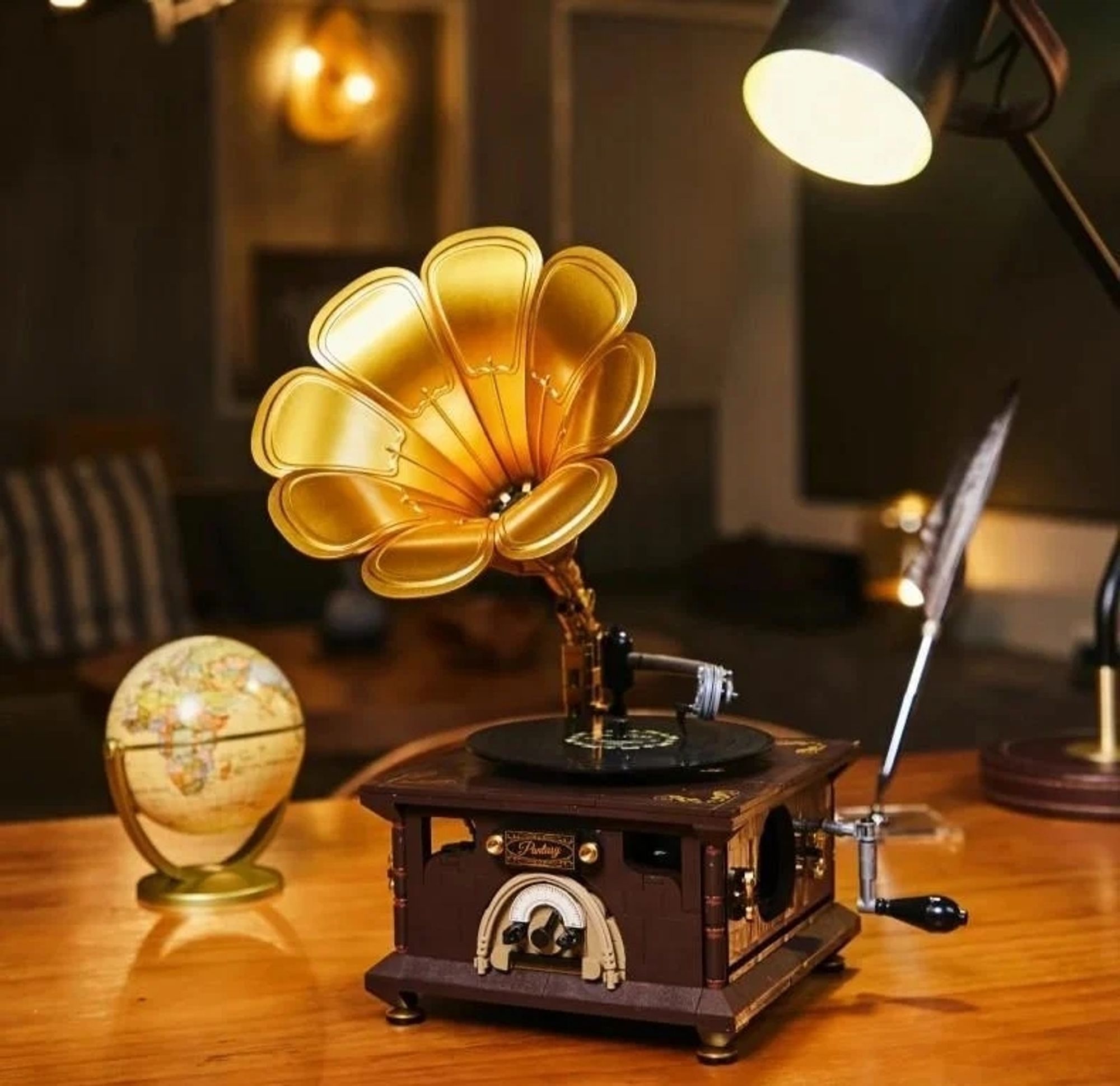 Ein Foto eines Retro-Grammophon aus Klemmbausteinen auf einem Schreibtisch, rechts daneben steht eine Schreibfeder, links daneben ein kleiner Globus