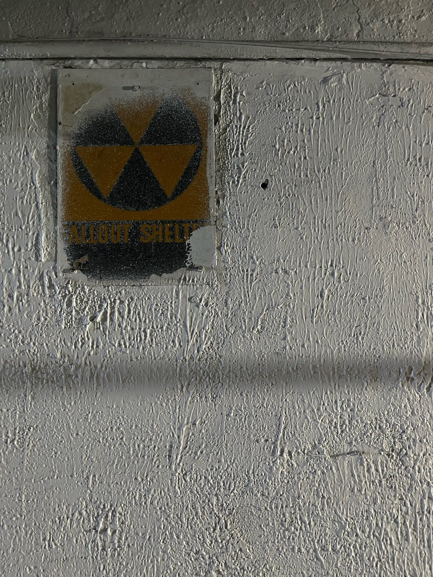 an old partially painted over fallout shelter sign in the basement of my sublet