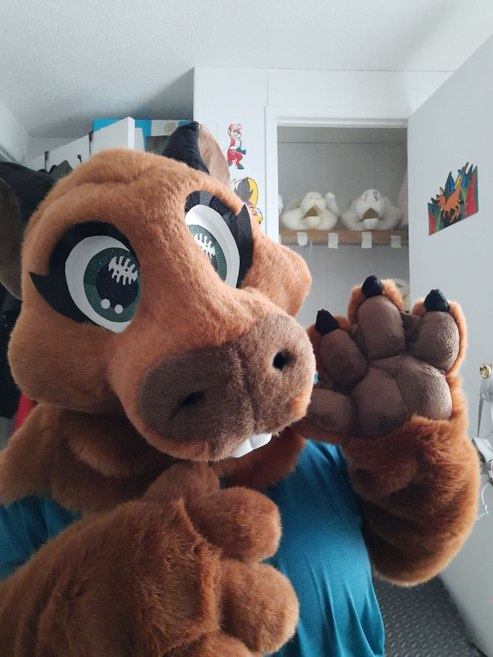 Photo of a toony capybara costume. One hand is raised up waving hi to the camera.