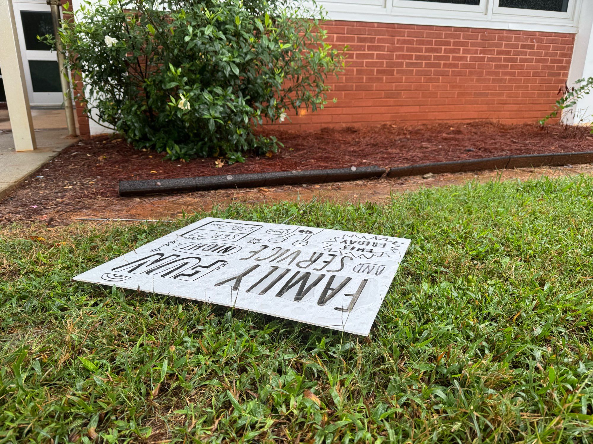 A sign outside an elementary school advertising family fun night tonight. The sign is laying flat on the ground after being blown over by wind from Helene.