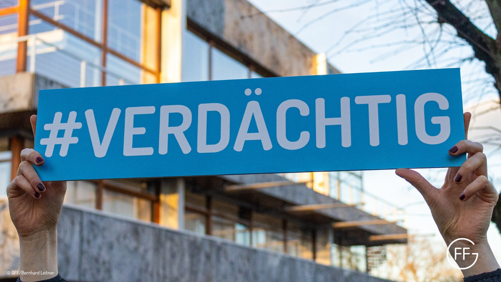 Eine Person hält ein Schild vor dem Bundesverfassungsgericht in Karlsruhe hoch. Auf dem Schild steht: #Verdächtig