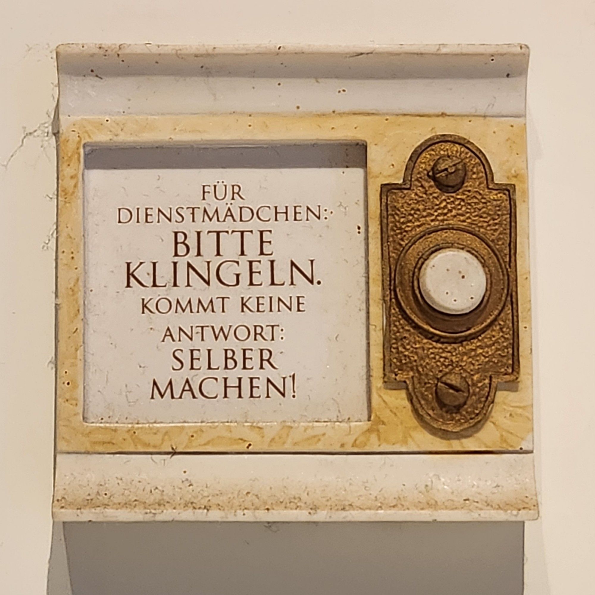 Klingelschild mit der Aufschrift "Für Dienstmädchen bitte klingeln. Kommt keine Antwort: Selber machen!