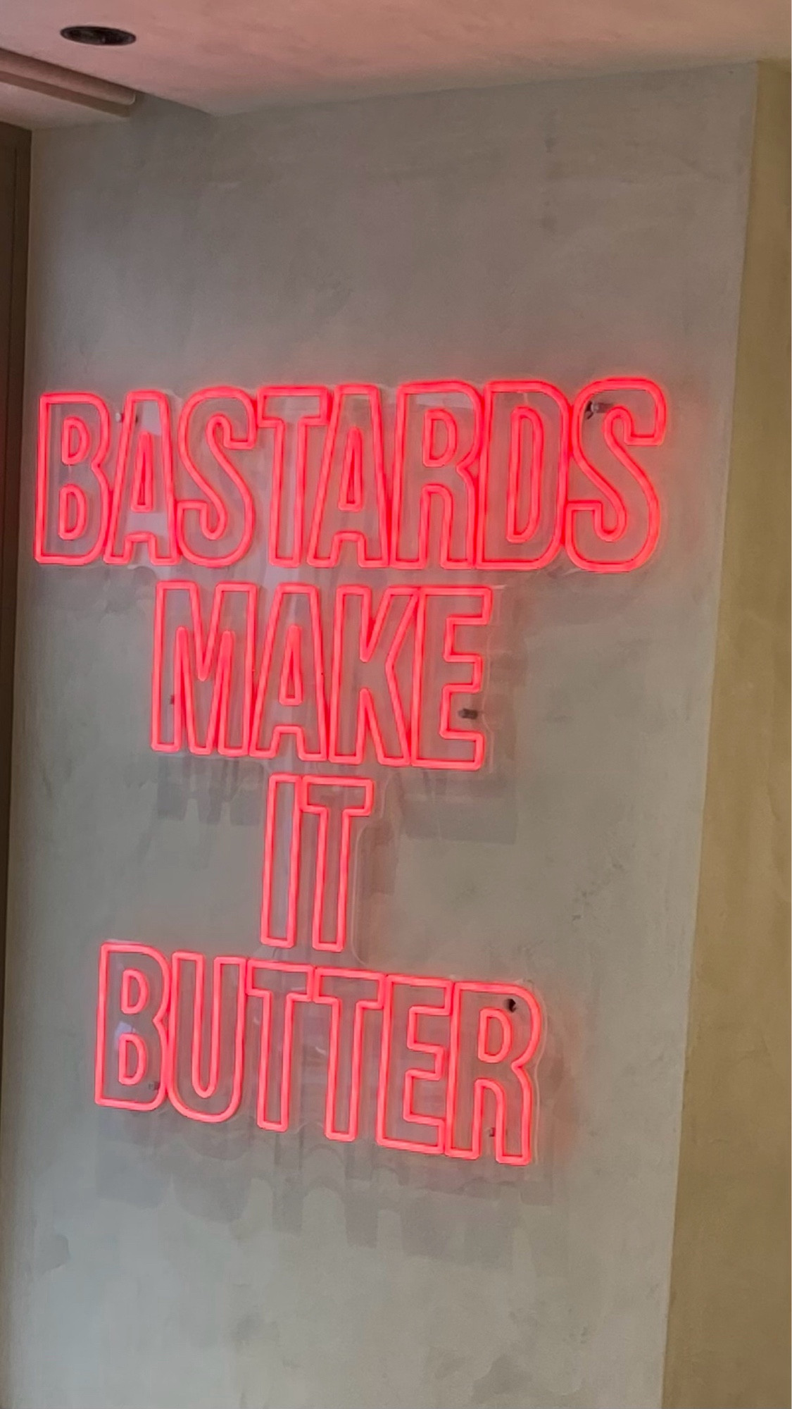 Leuchtende Letter in neonorange „Bastards make it butter“