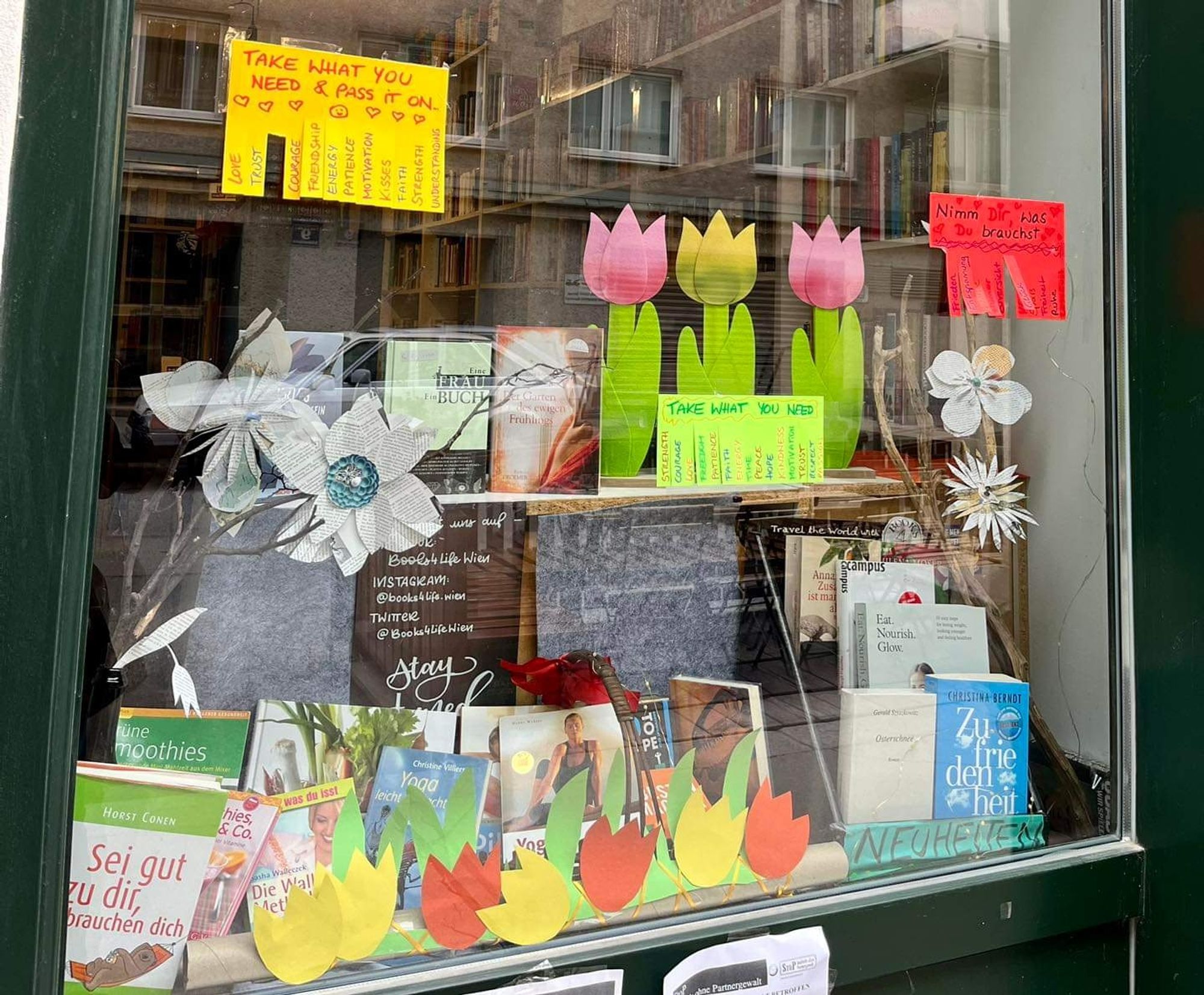 Unser Schaufenster erstrahlt frühlingshaft: voller Bücher zum Frühling und bunten Papierblumen