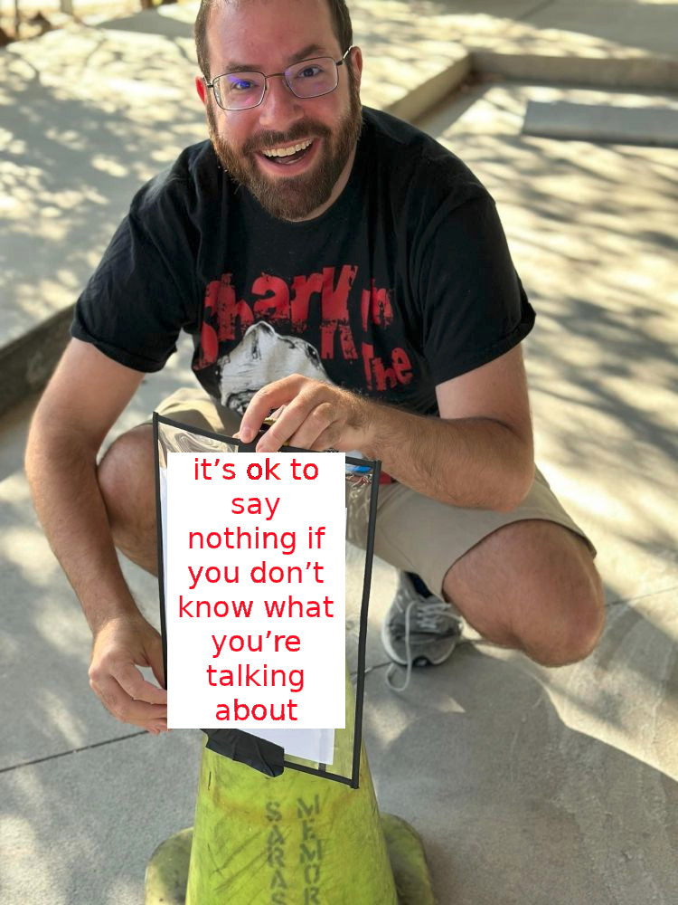 Man holding a sign that says "it’s ok to say nothing if you don’t know what you’re talking about"