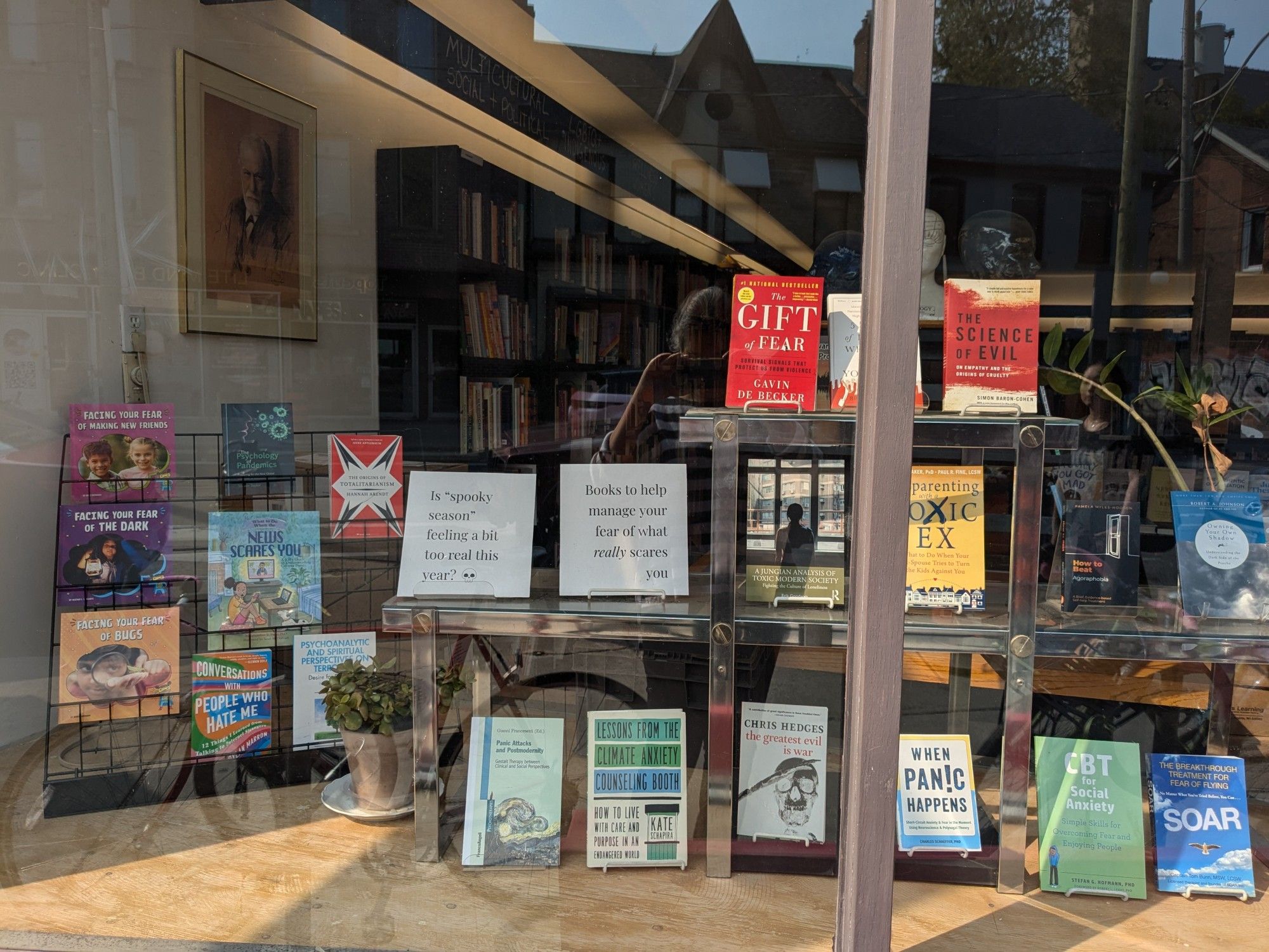 A bookstore window display of books about truly scary things, including the news, toxic exes, climate change, war and terrorism, social interaction, pandemics, etc.