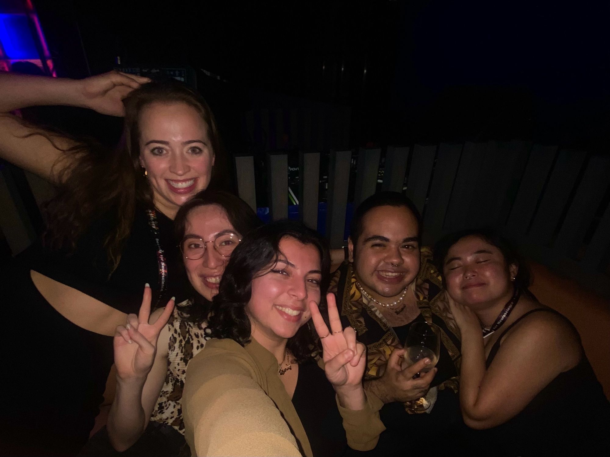 Five smiling friends taking a selfie in a dark bar