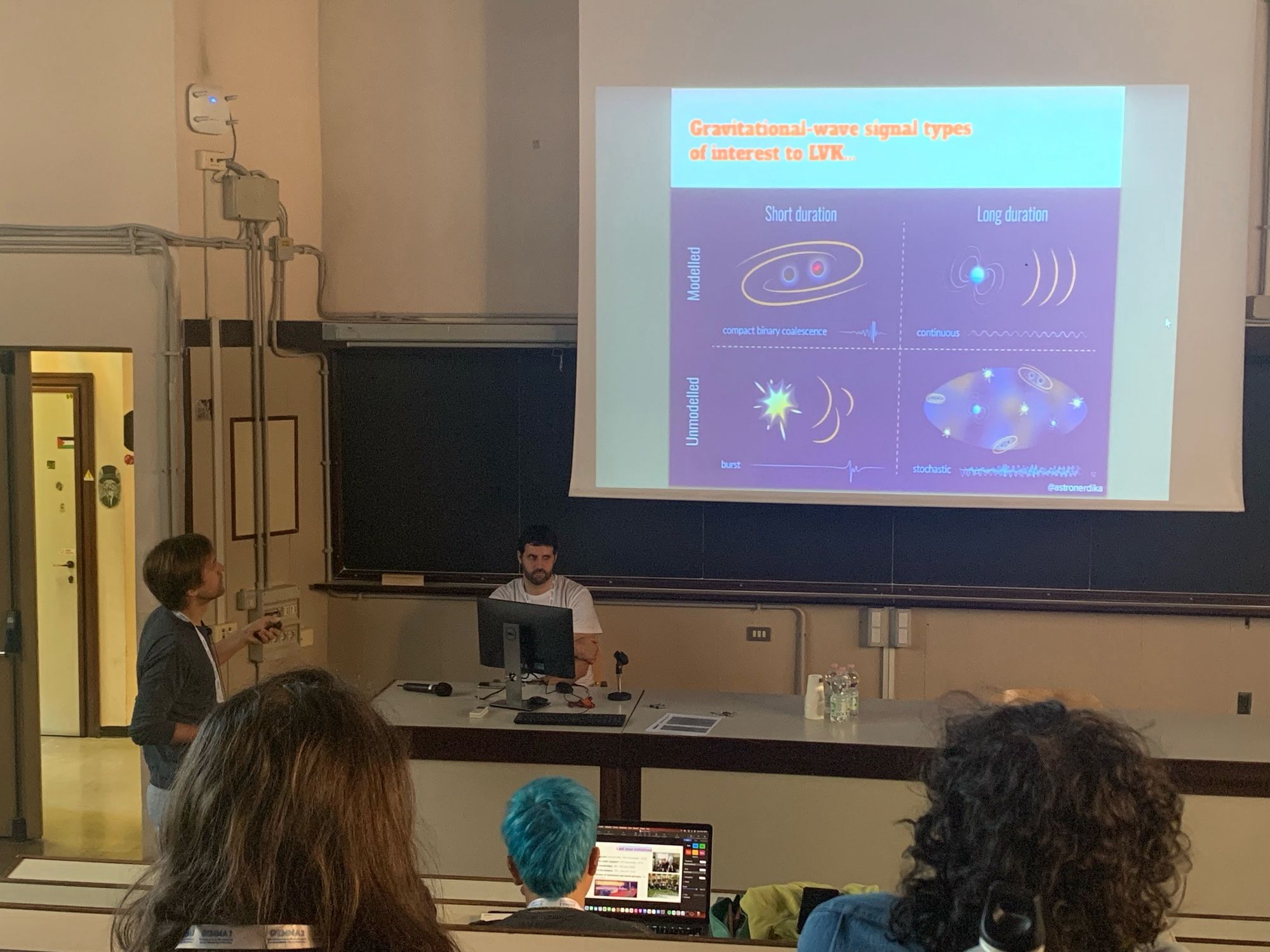 A person presenting some slides to an audience in a lecture room.