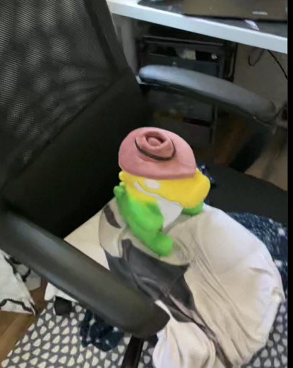 a photo of a smiling neon green and yellow alligator plushie wearing a cowboy hat sitting in a chair