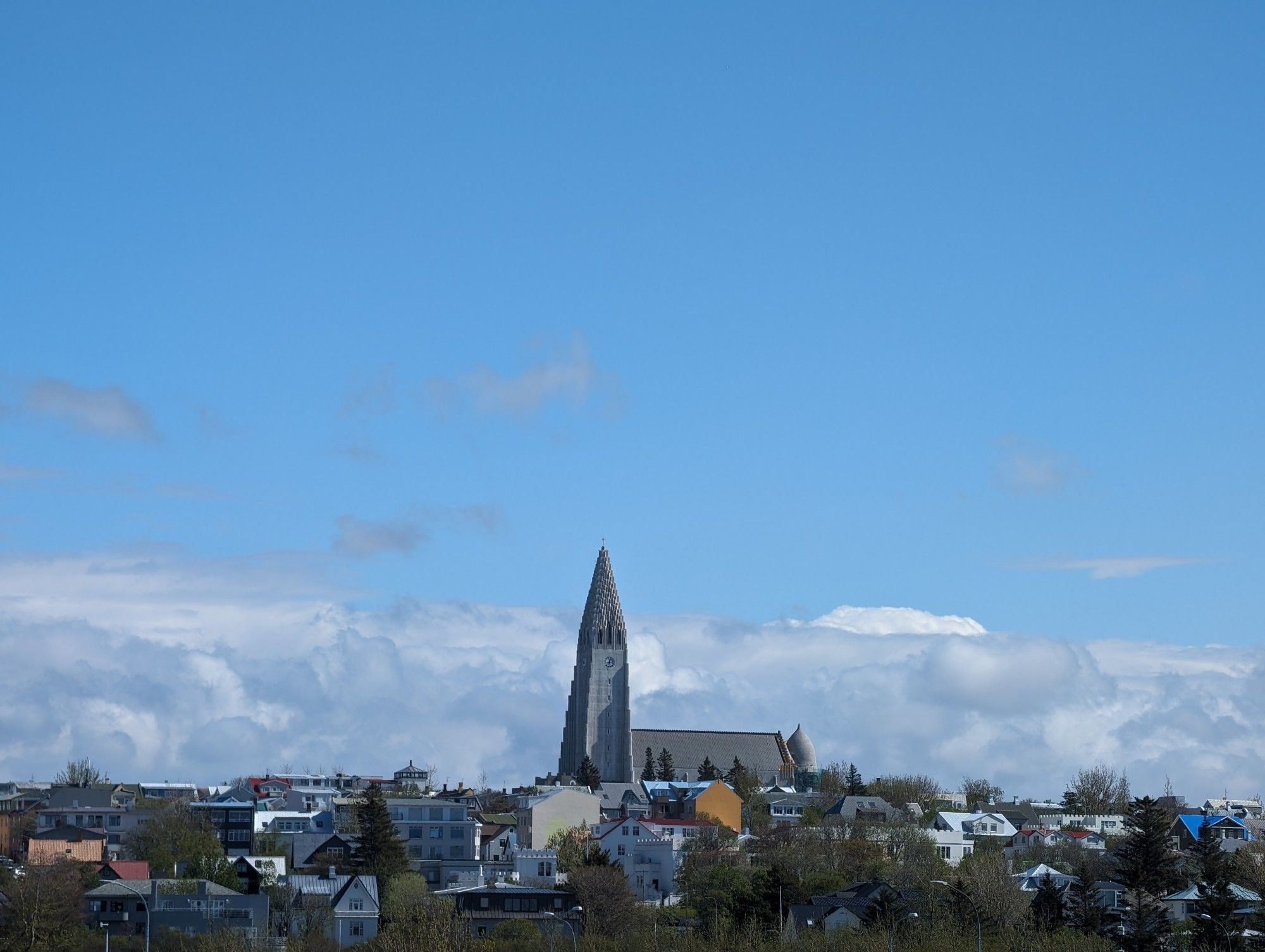 The big church in Reykjavik with blue sky behind it and clouds on the horizon