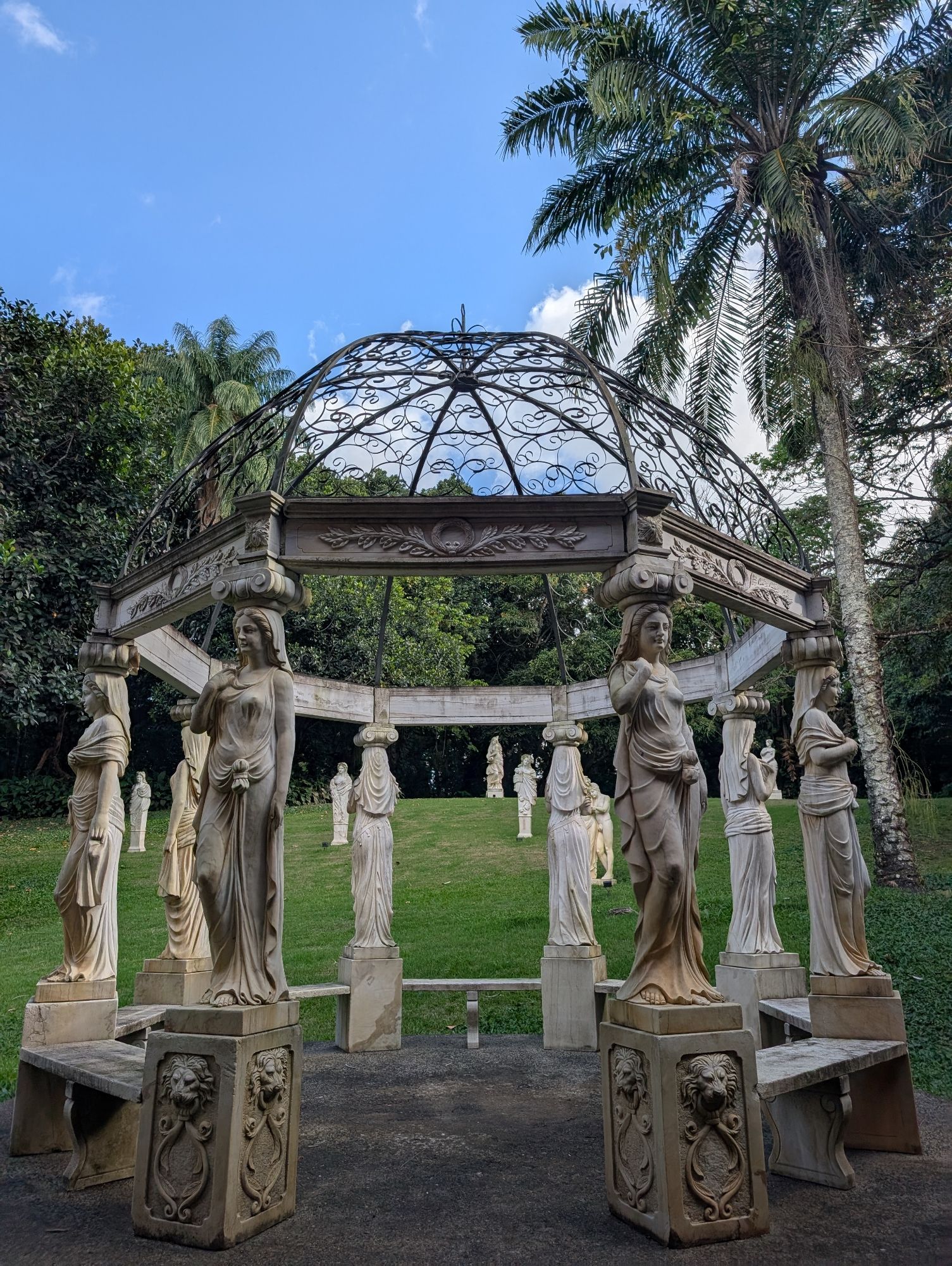 A gazebo held up by Greek statues, in a sculpture garden