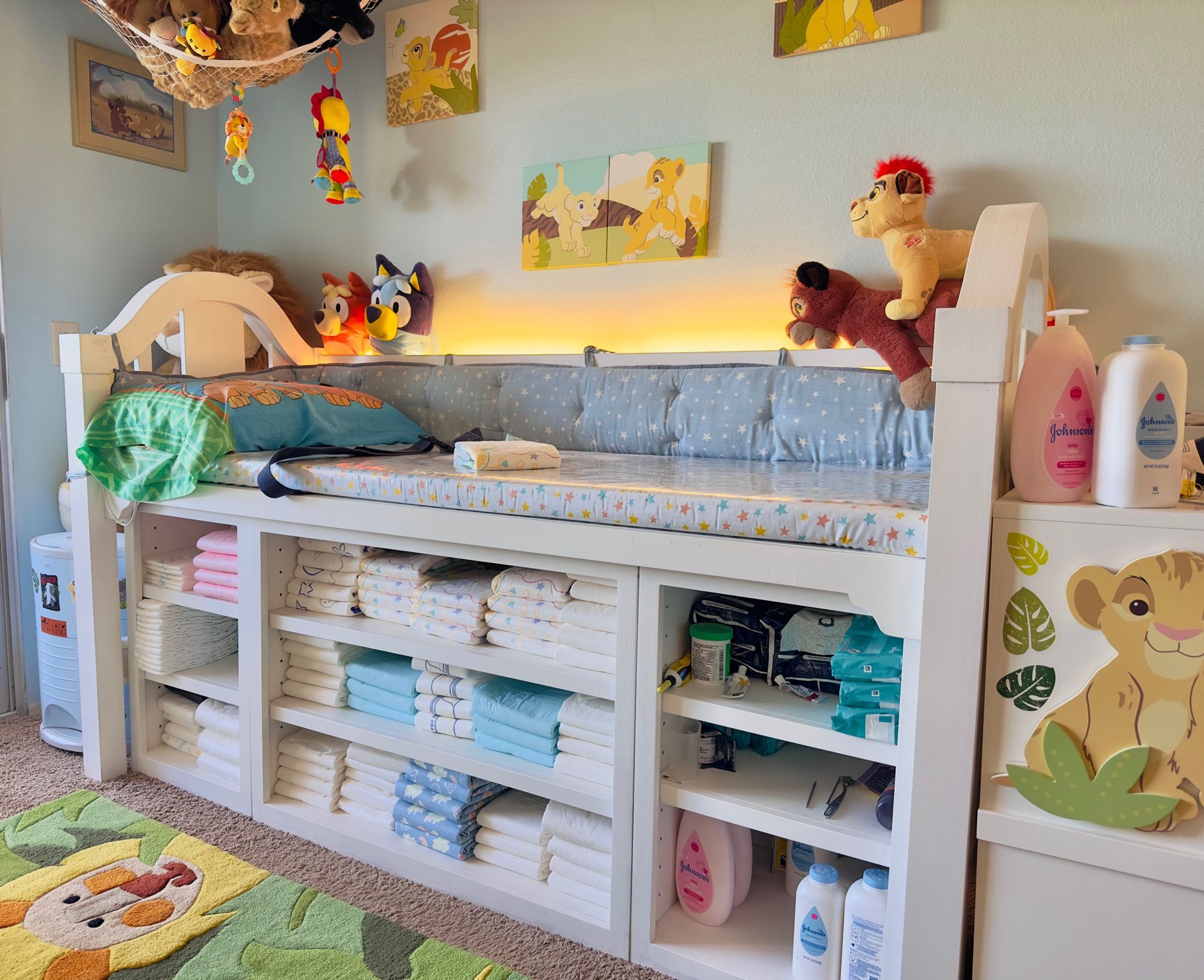 A large changing table fit for an adult boy. With a soft vinyl lined topper, a big strap to hold a fussy one down, stacks and stacks of diapers, and enough soft toys to distract a boy getting his bottom wiped.