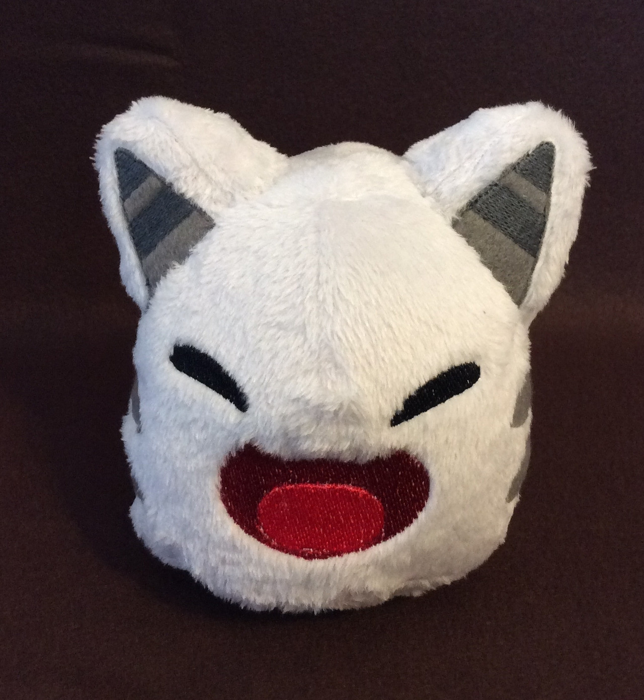 A handmade Tabby Slime plushie.  It is made of grey minky with embroidered face and ears.