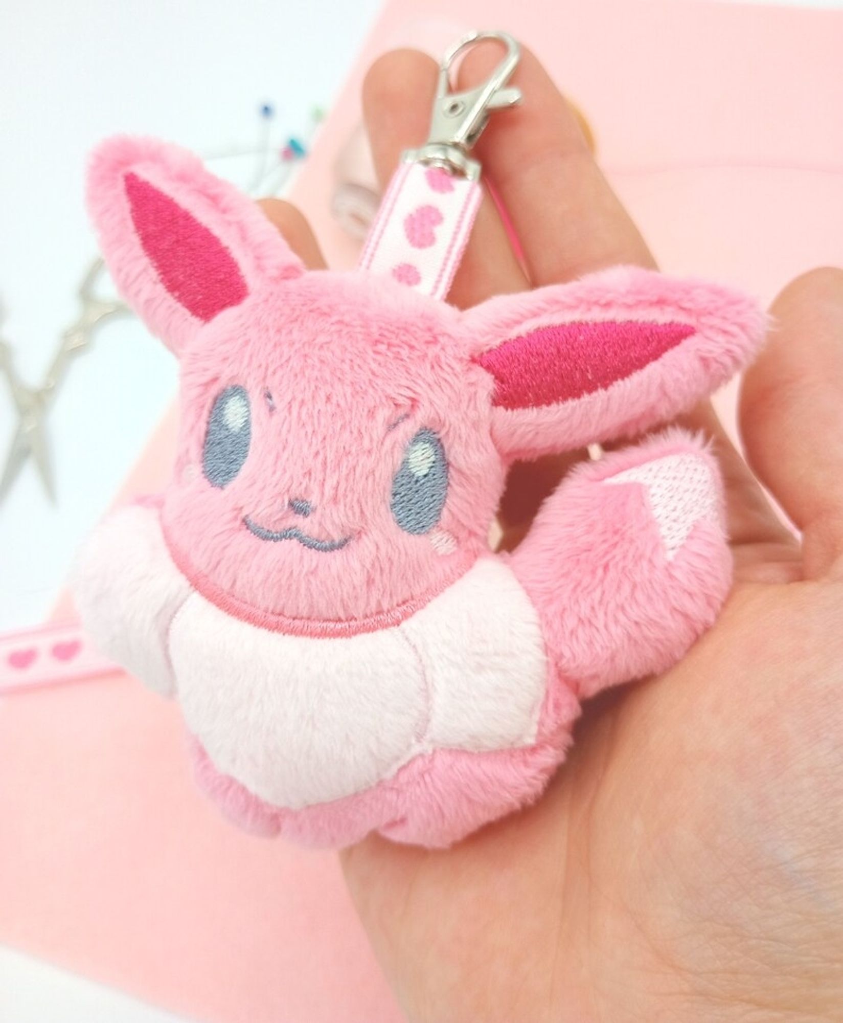 A handmade pink Eevee plushie keychain from the Pokemon video game series.