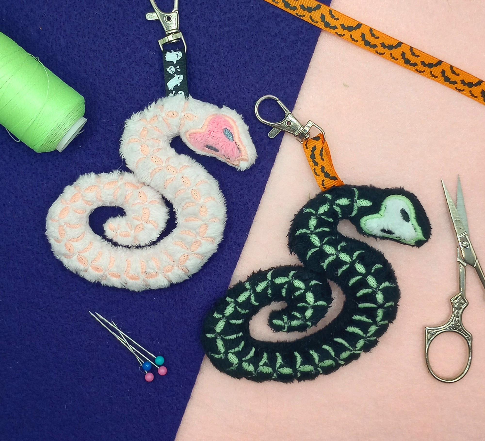 Two handmade Skeleton Snake plushie keychains.  The left is pink and the right is black.