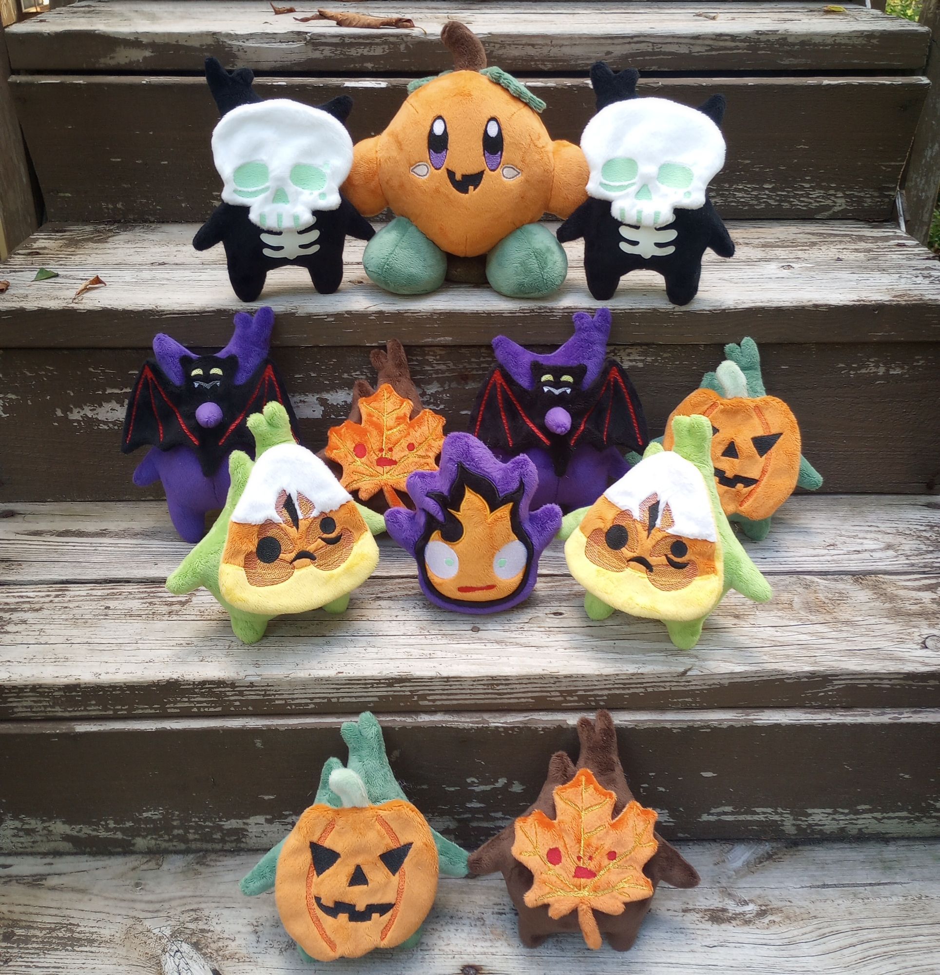 A collection of handmade Halloween themed plushies.  Includes Koroks from the Legend of Zelda, Calcifer from the Studio Ghibli movie Howl's Moving Castle, and Kirby.