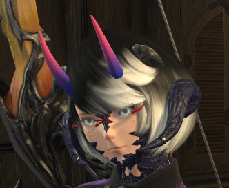 A cropped screenshot from the MMO FFXIV, which is a close up on a player character's face. The character is in a wood paneled room and has a bow strapped to their back which is yellow-orange with black accents. The character is a female Xeala, which is a race of humanoids with dark blue scales, horns and tails. The character has a short black bob with a white gradient towards the bottom. She also has two sets of dragon like horns, one long set that appears to start where the ears would be and a second much smaller set near the temples. The character's face has scales around the jawline, and bridge of the nose as well as down the chin and onto the neck. They wear a pair of rimless glasses, the frames are a bright red. Their eyes are a dark purple in colour with a neon blue limbal ring on the outside. A third set of horns, more akin to a traditional demon horn, rise from their forehead. These horns are smooth and start with a deep blue at the bottom, transition to purple and then end in pink, very similarly to the bisexual pride flag. 