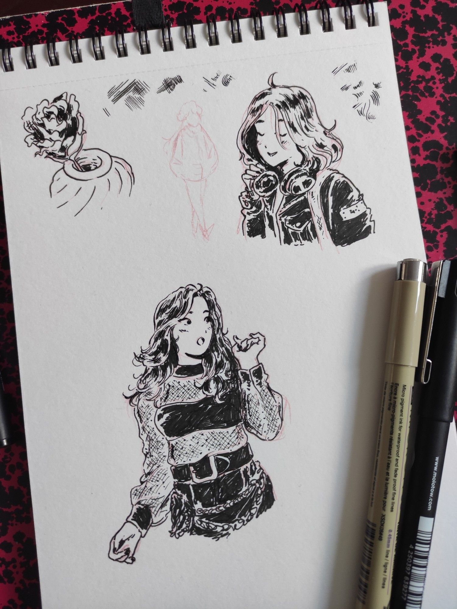 sketchbook page with drawings of two women, one is an idol singing, the other someone with a leather jacket and big headphones 
Also a tiny flower in a vase