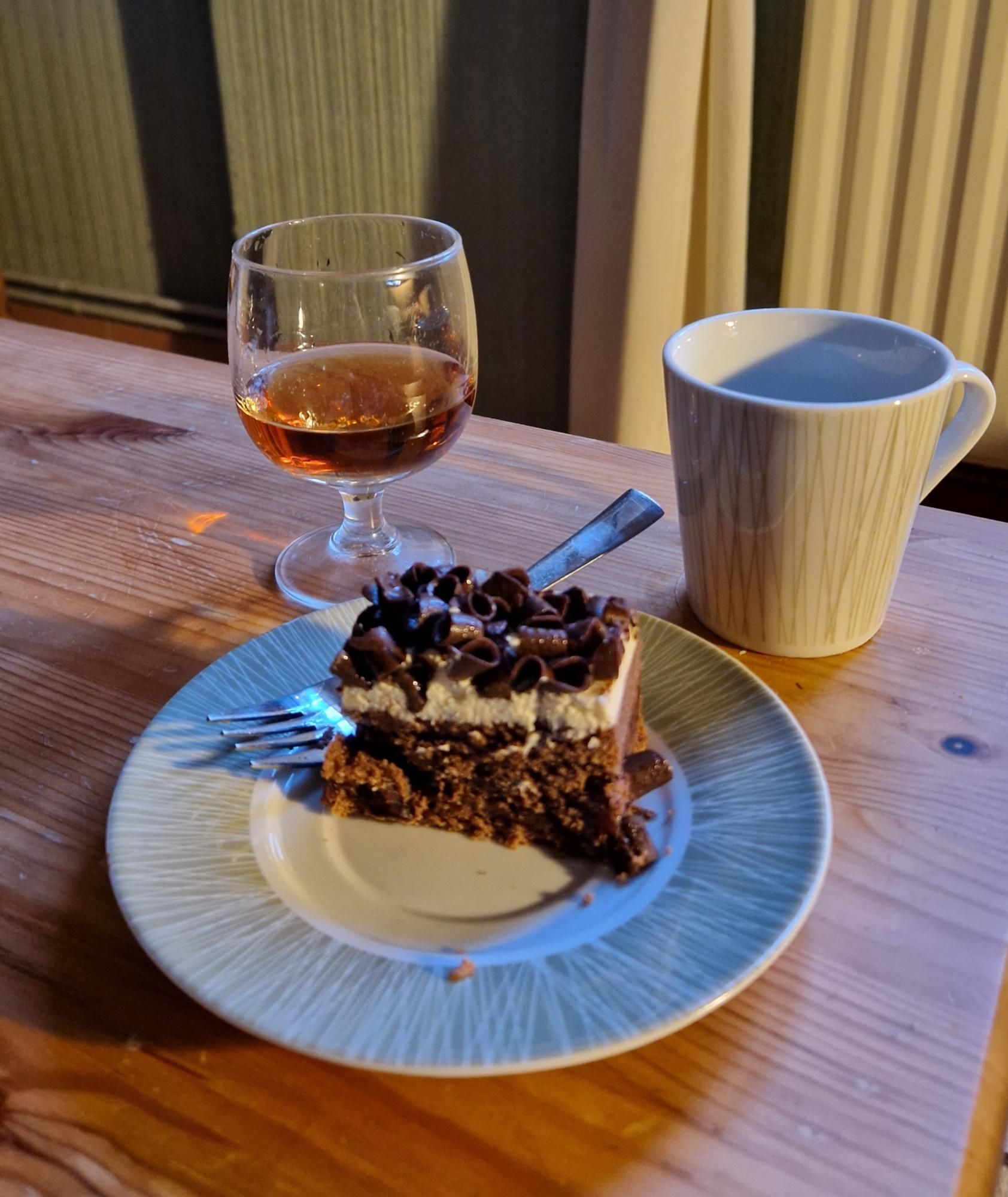 Kop koffie, glas armagnac, forêt noir gebakje.